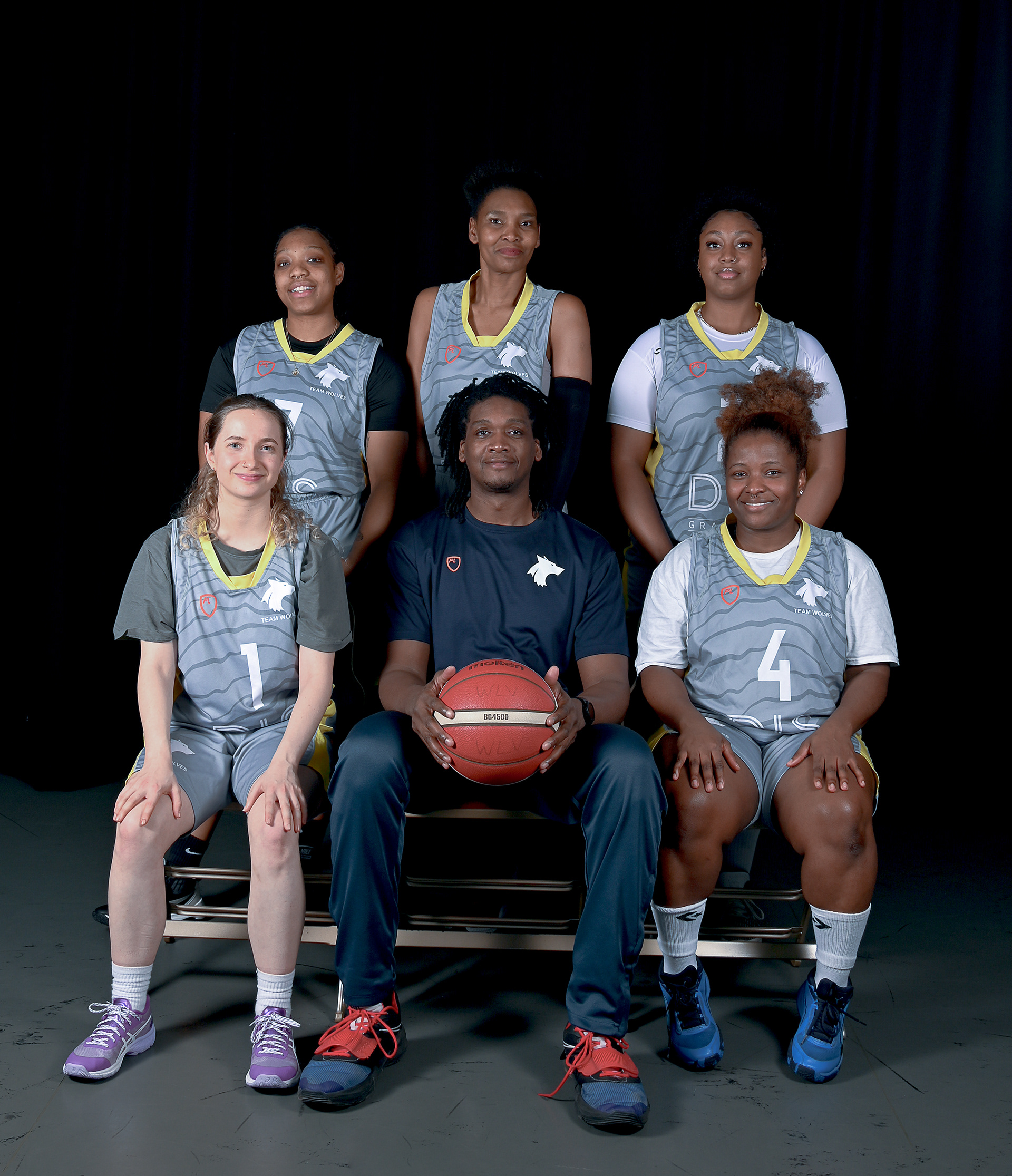 A group of young women with one man who holds a basket ball
