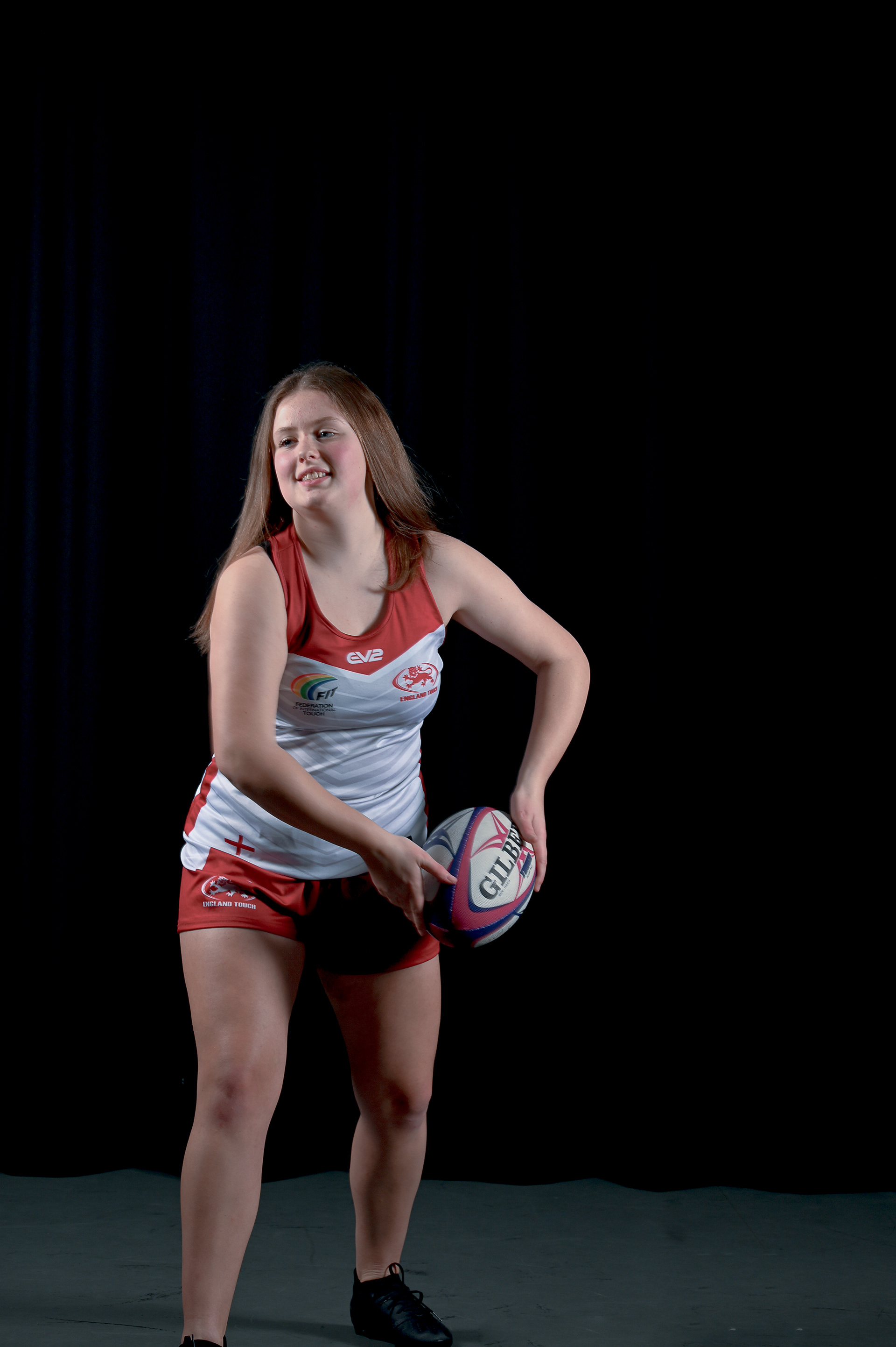 A young women in sports wear pretends to throw a rugby ball