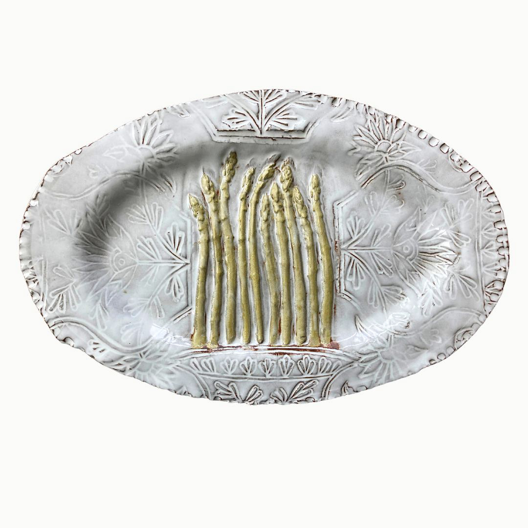 on a white ground a handmade ceramic platter with raised asparagus details over a de-bossed delicate white floral pattern.