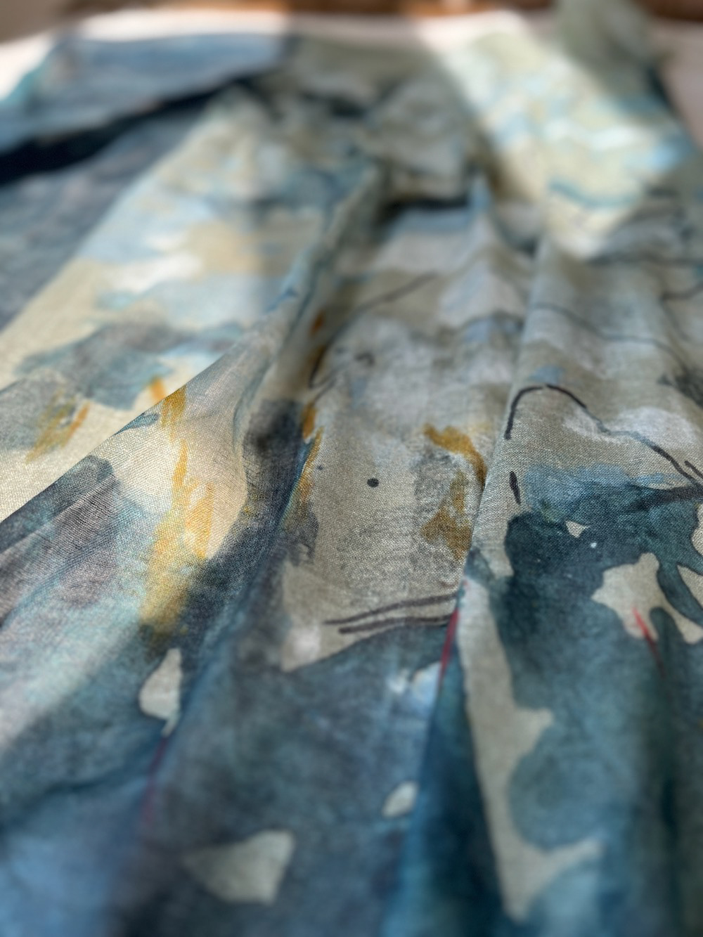 Hanging textile wall art (Folded view 1): vibrant cypress tree illustration with sunlight filtering through branches. Colors range from silvery teals to deep indigo, with warm sienna red accents