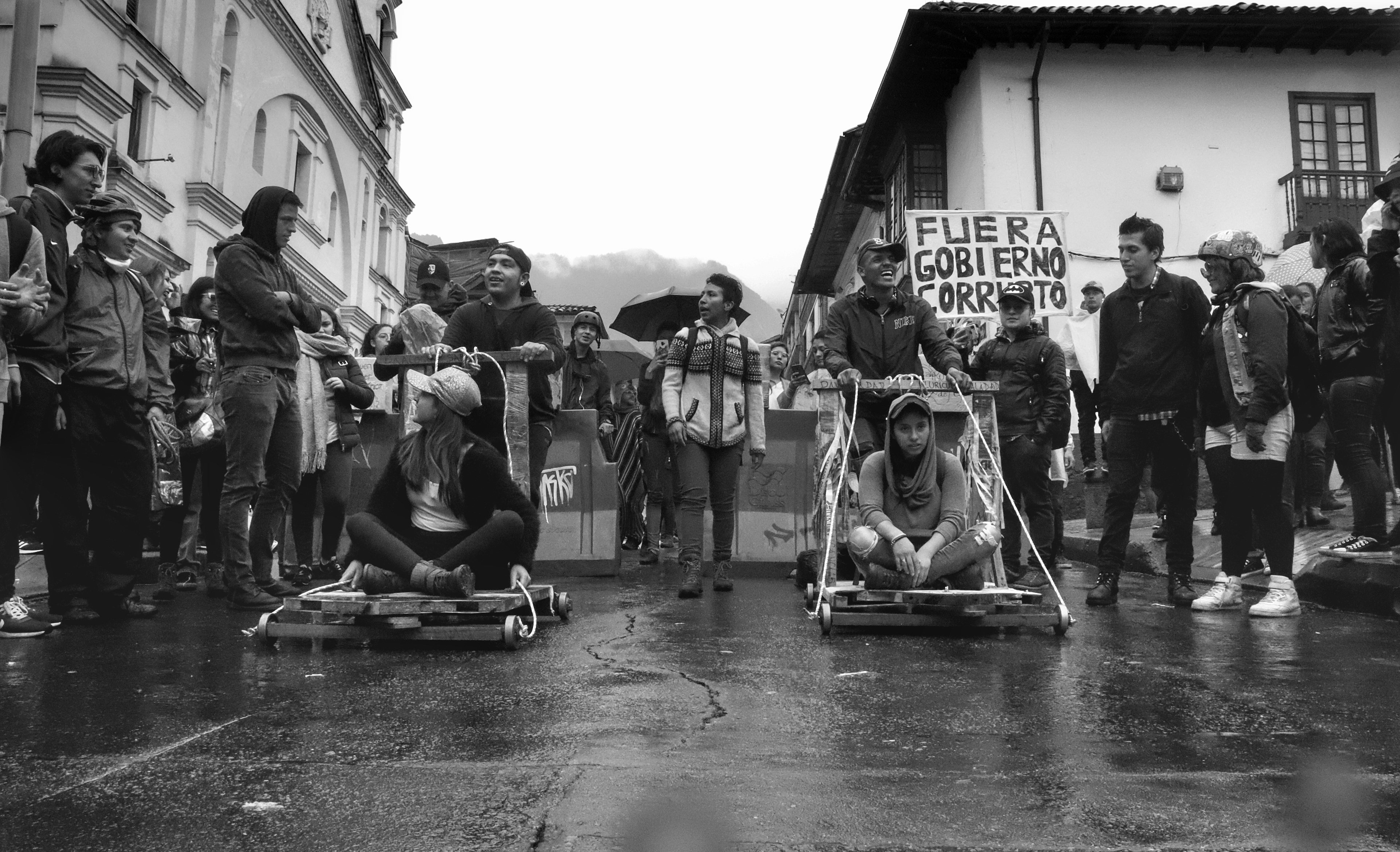 En algún lugar de Bogotá estudiantes se reúnen a competir en carros de balineras después que una intensa lluvía aplaca los ánimos de protestantes y autoridades anti disturbios dentro del marco del paro nacional del 21 de Noviembre.