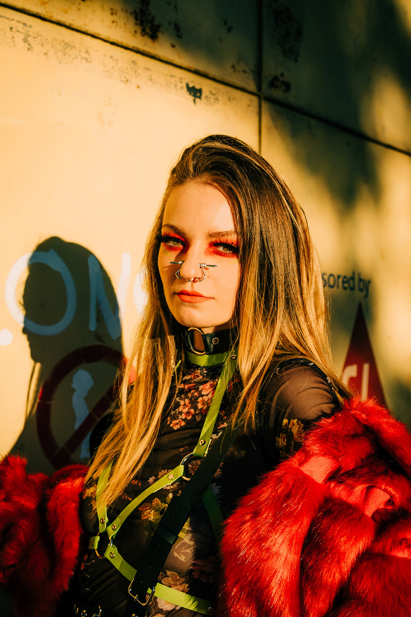 Portrait of a girl with nose piercing wearing a harnish and red fur coat