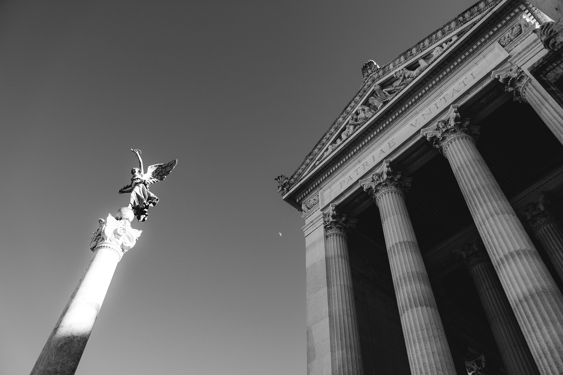 Low angle monochrome shot showing part of the Victor Emmanuel monument and a victory column