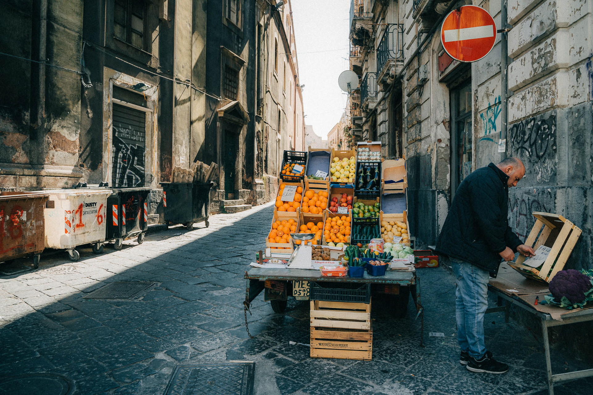 Man working at a small fruit stand in the streets of Catania