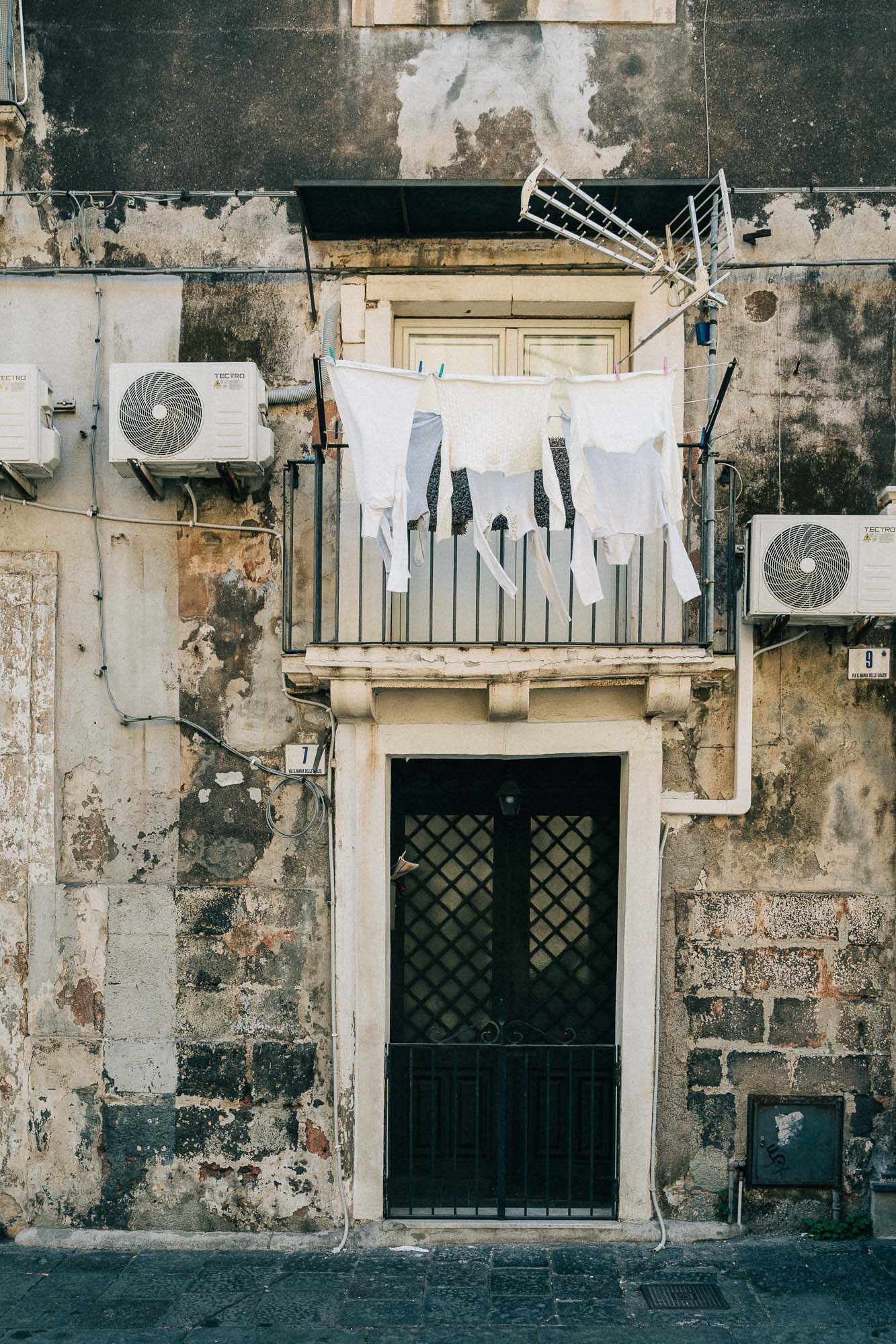 White laundry hanging over a black door in the streets of Catania