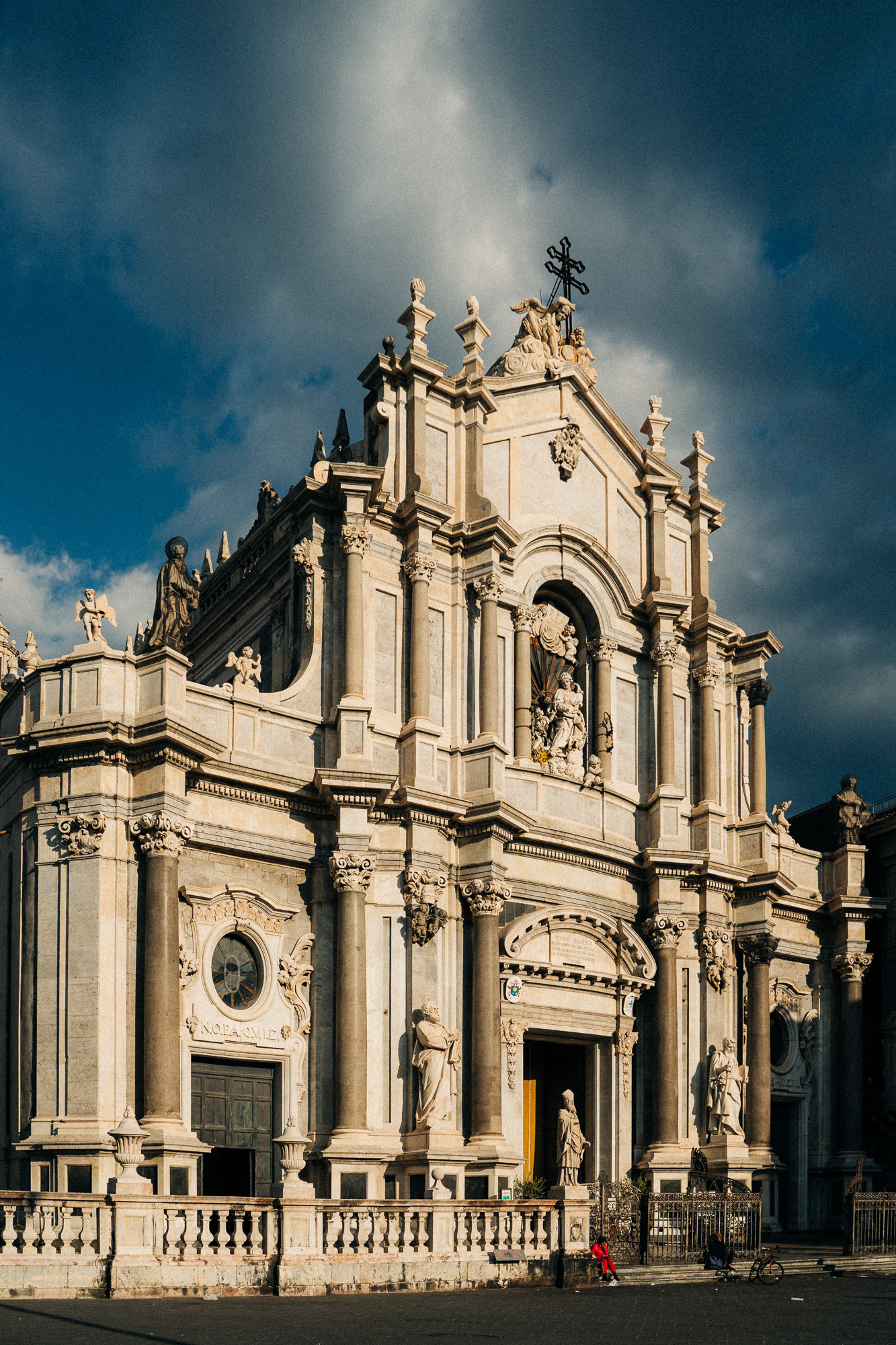 Travel photography showing Catania's Sant'Agata cathedral being sunlit with dark clouds in the sky