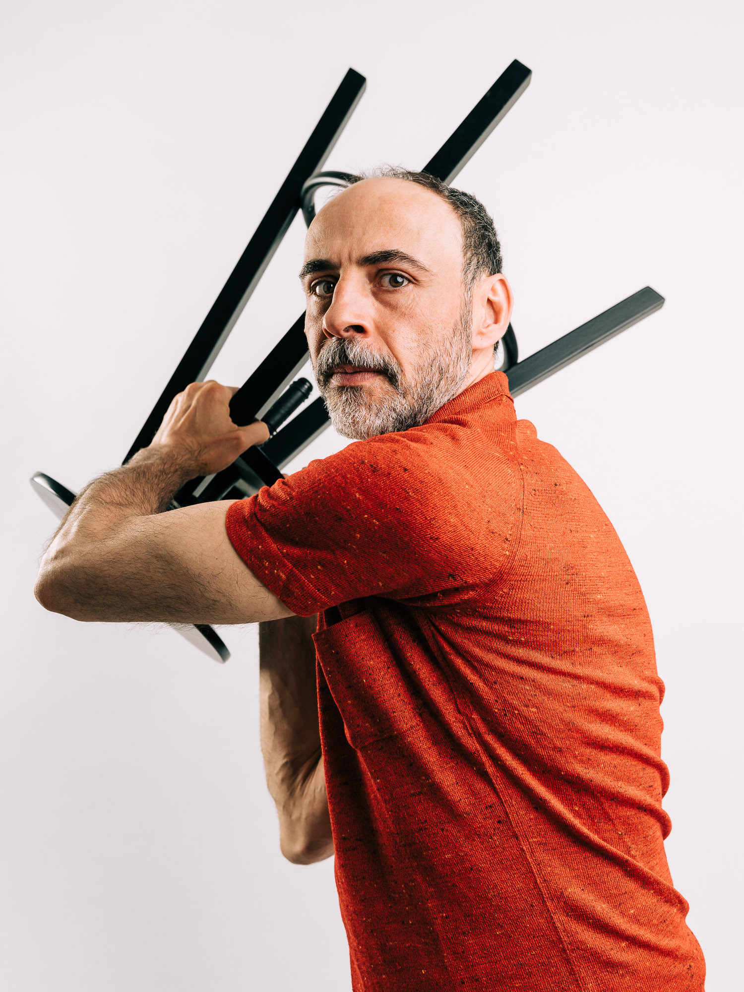 Studio portrait of Florian Tröbinger with a stool in his hands