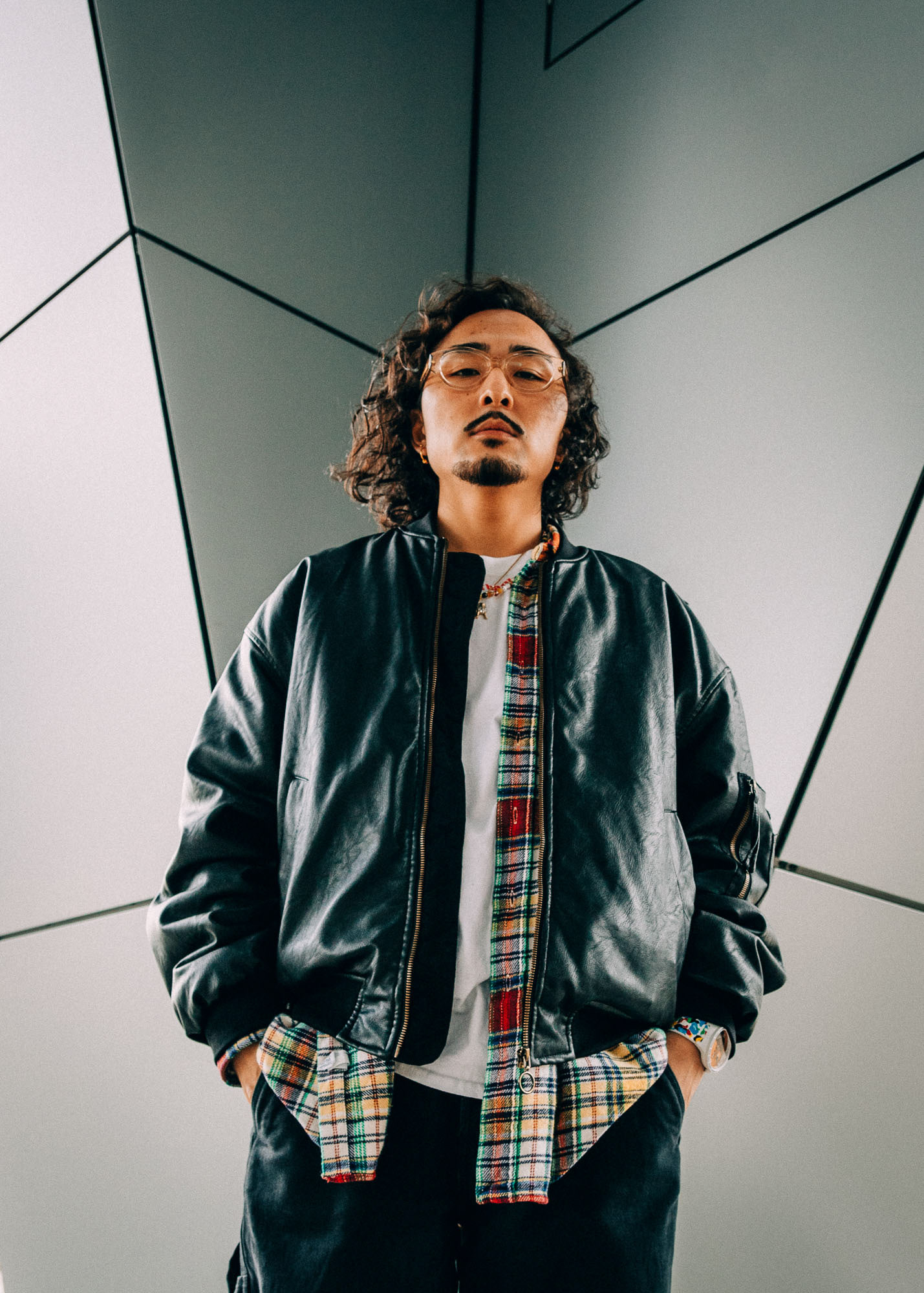A young Asian man stands in front of a geometric background for a portrait photo