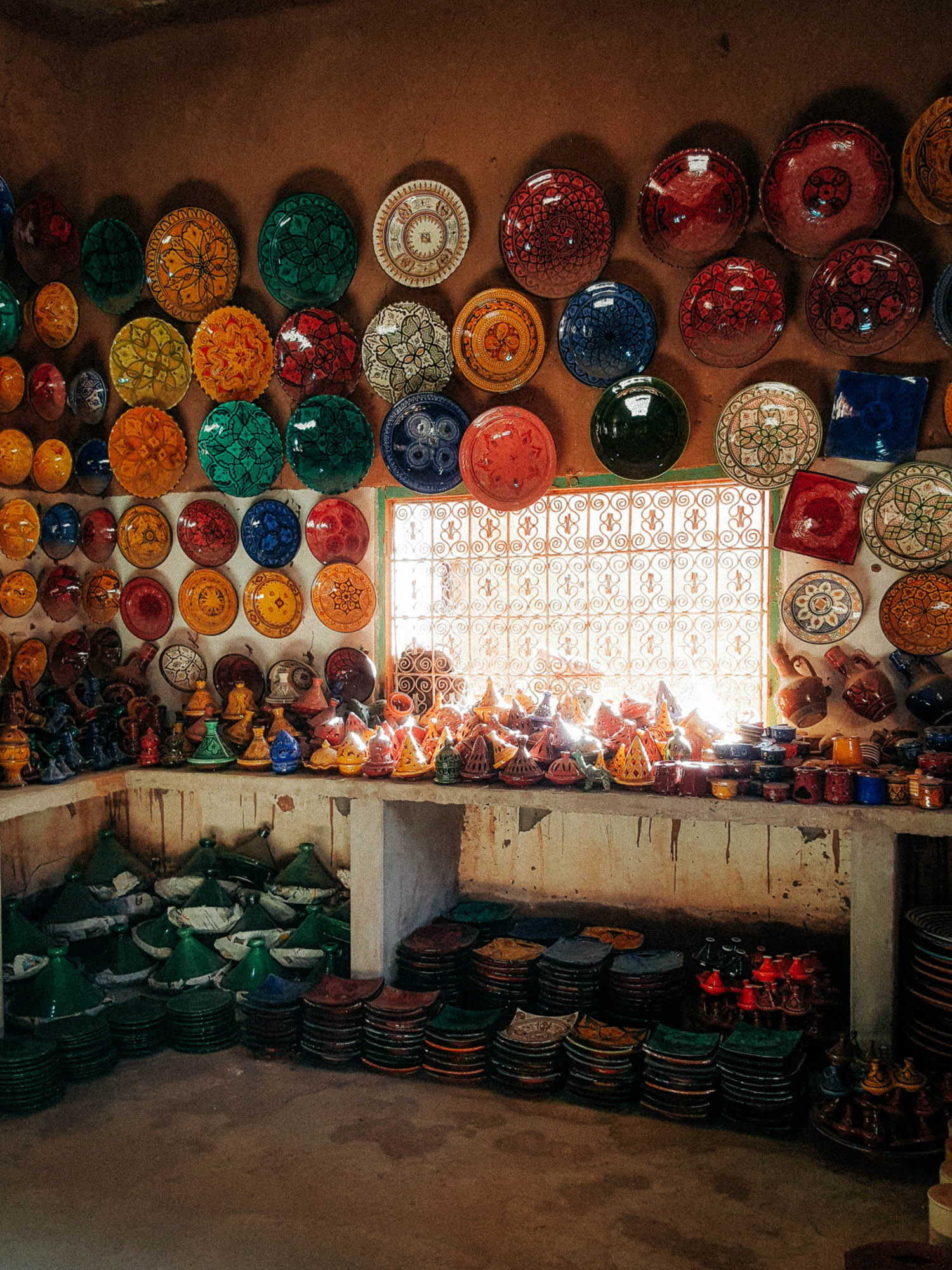 various colourful handmade tajines and plates on display in a traditional Moroccan pottery