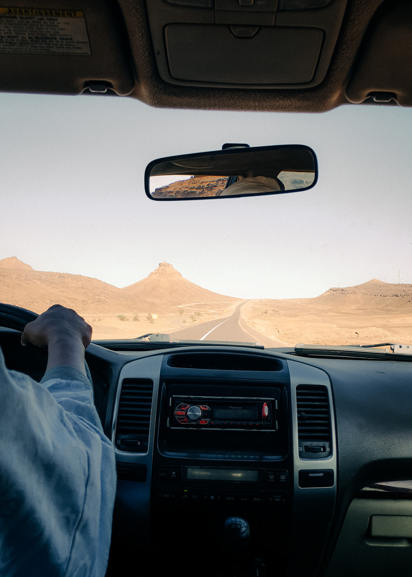 View of a road going through the Moroccan desert photographed through a car windshield