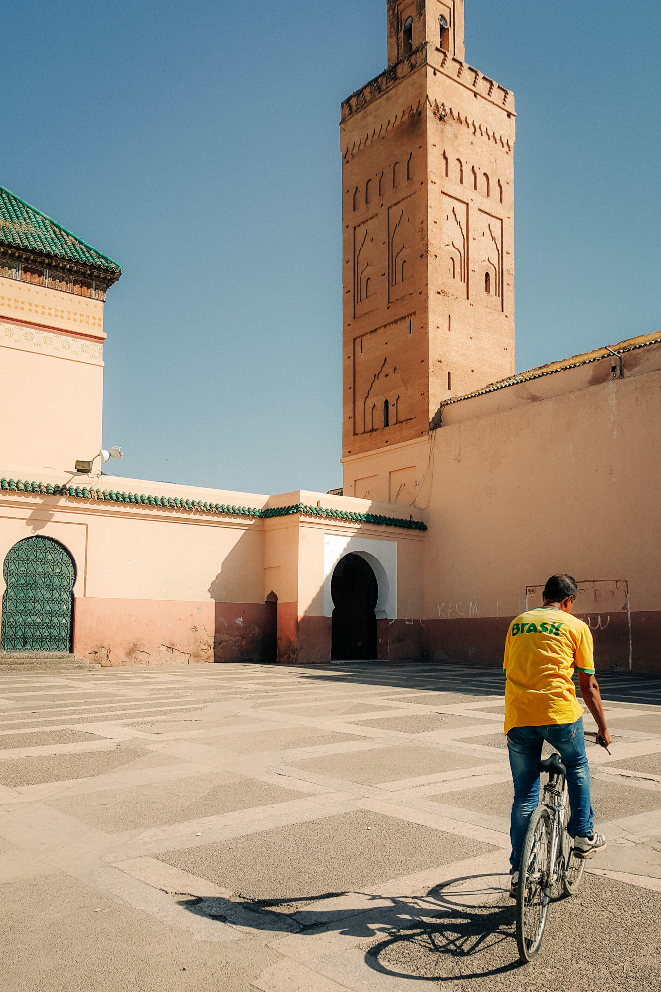 A man in yellow t-shirt rides his bike through an empty square in the Medina of Marrakech