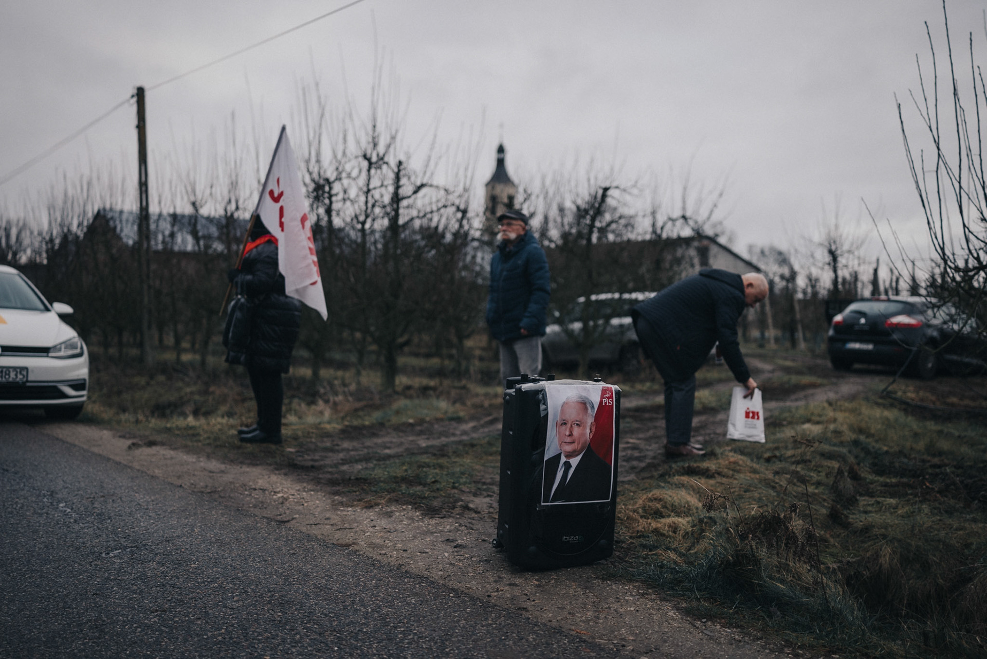 Community members gather before Karol Nawrocki’s appearance; a loudspeaker playing right-wing songs is adorned with a poster of Jaroslaw Kaczynski.