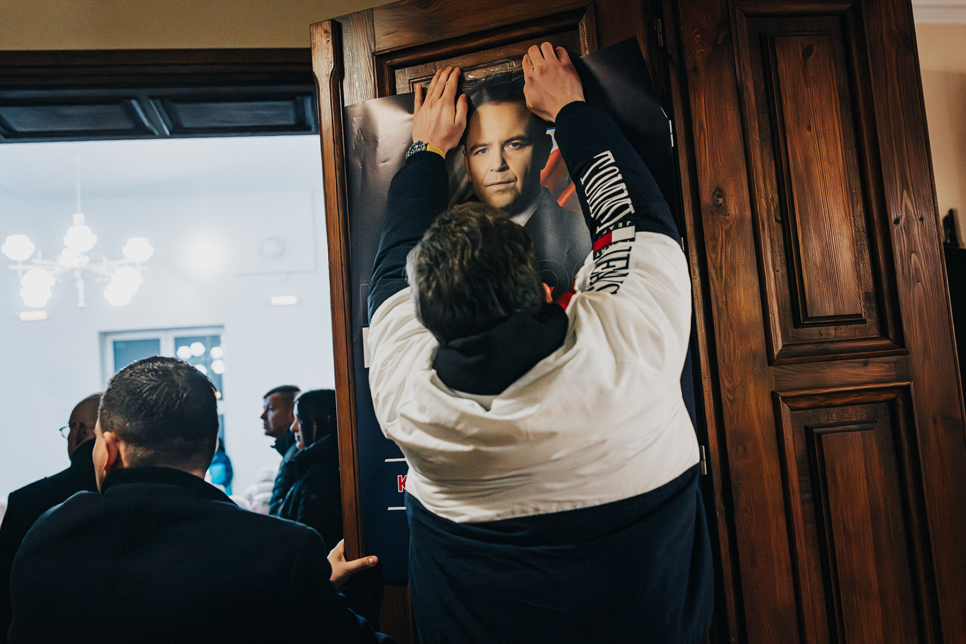 A campaign staffer attaches Karol Nawrocki’s poster to the door before the start of the event.