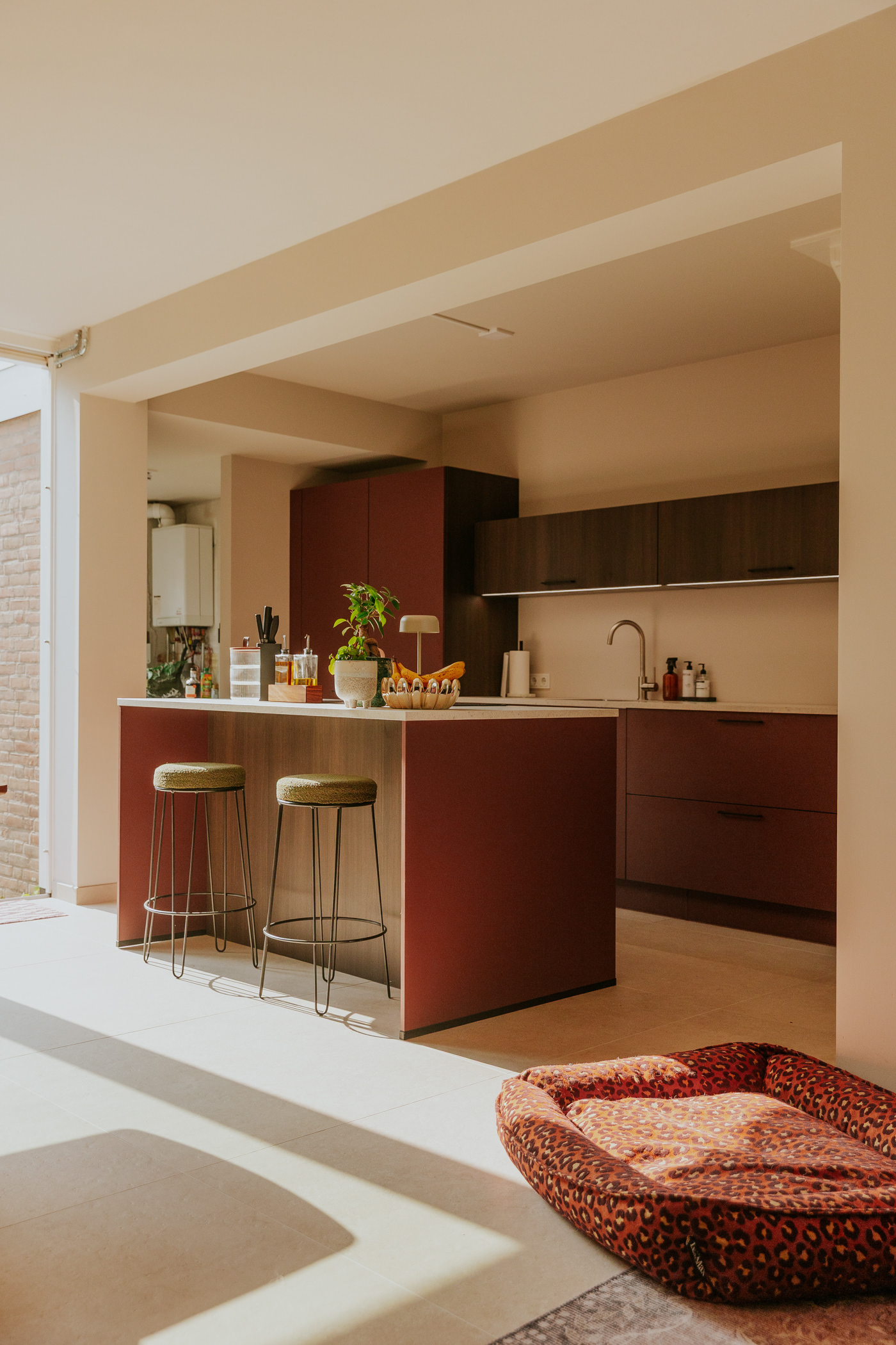 Interieurfotografie van een modern maatwerkinterieur met keuken, warme houttinten en natuurlijk zonlicht.