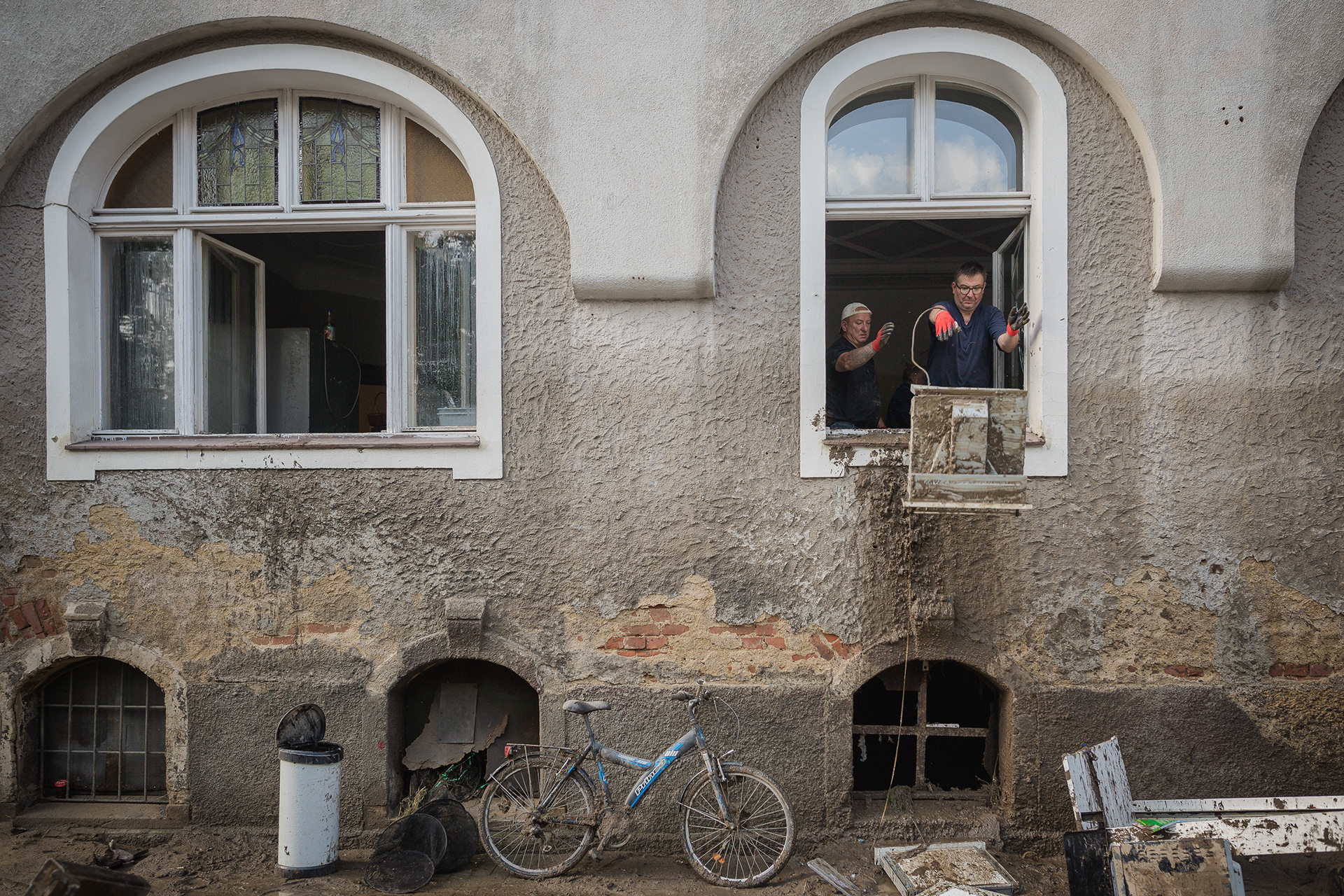 The apartment owner, together with a friend, is removing flooded and damaged household appliances that became unusable after the flood that struck Lądek-Zdrój in 2024. Photo © Marek Ladzinski / FORUM.