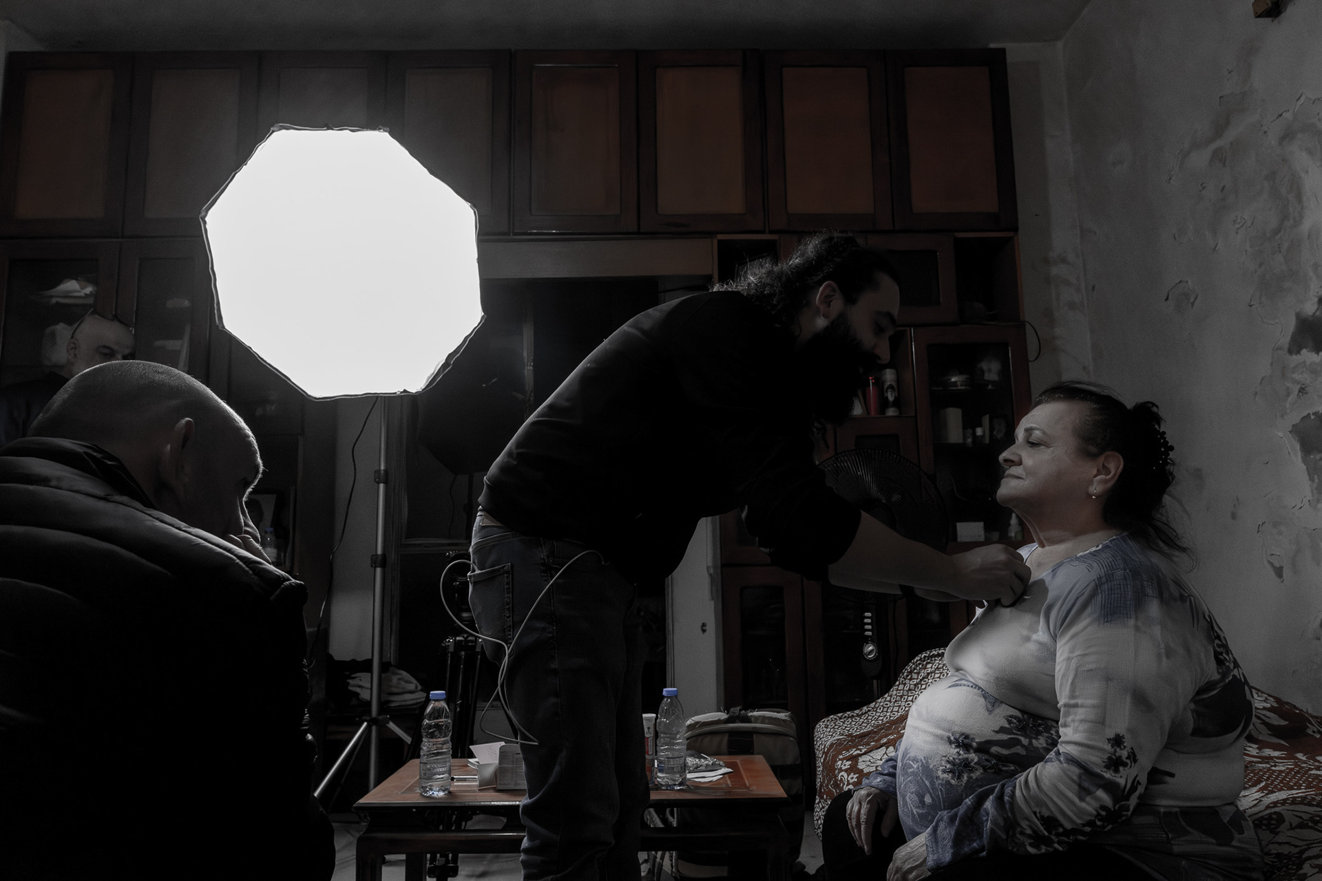Fatima during microphone setup before the interview in her temporary home in Amchit, with her son attentively watching her in the background. Photo © Marek Ladzinski.