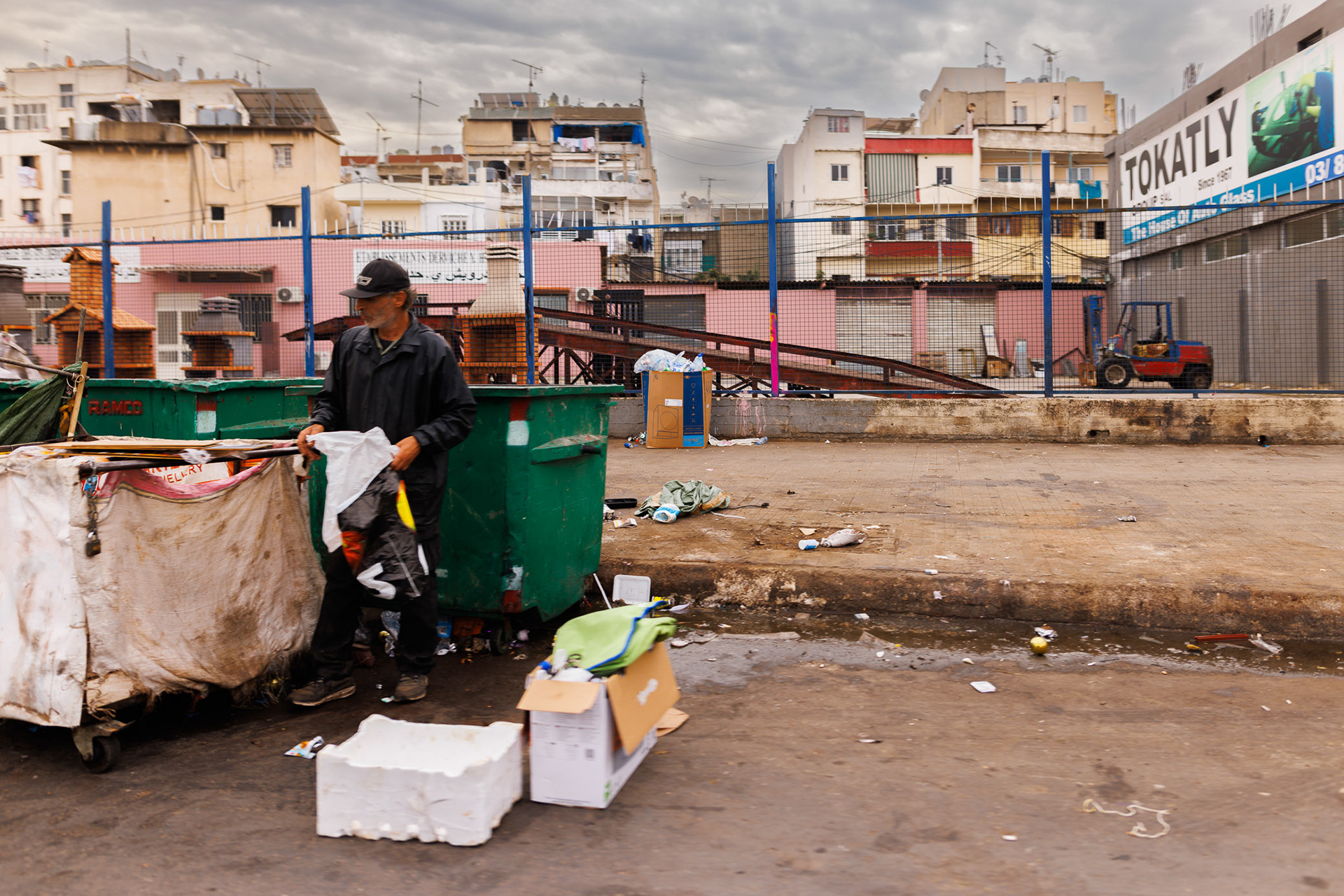 A man searches through a dumpster in front of an apartment block in southern Beirut. Photo © Marek Ladziński / FORUM
