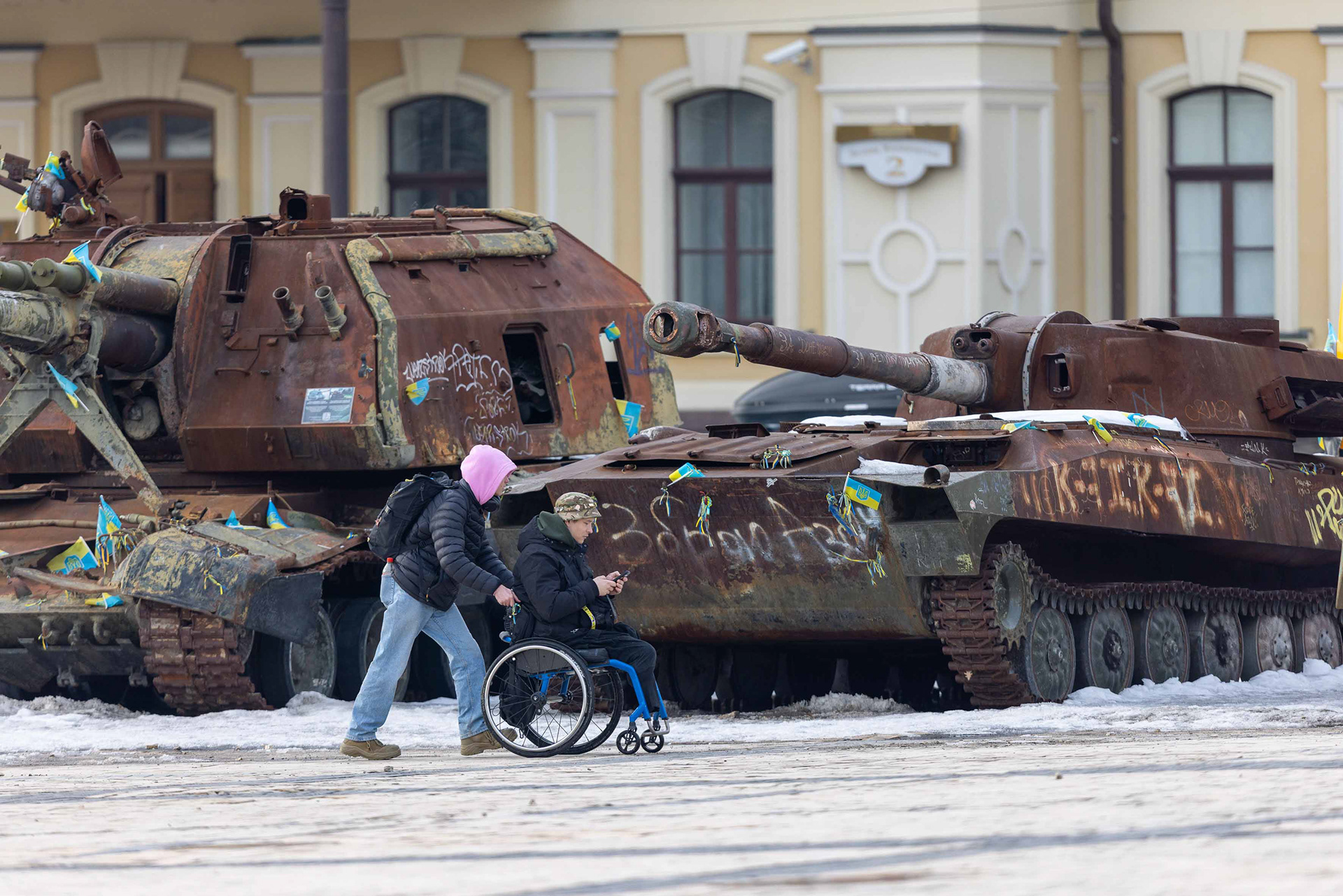 Wheelchair user passing destroyed military vehicles. © Marek Ladzinski / Zuma Press