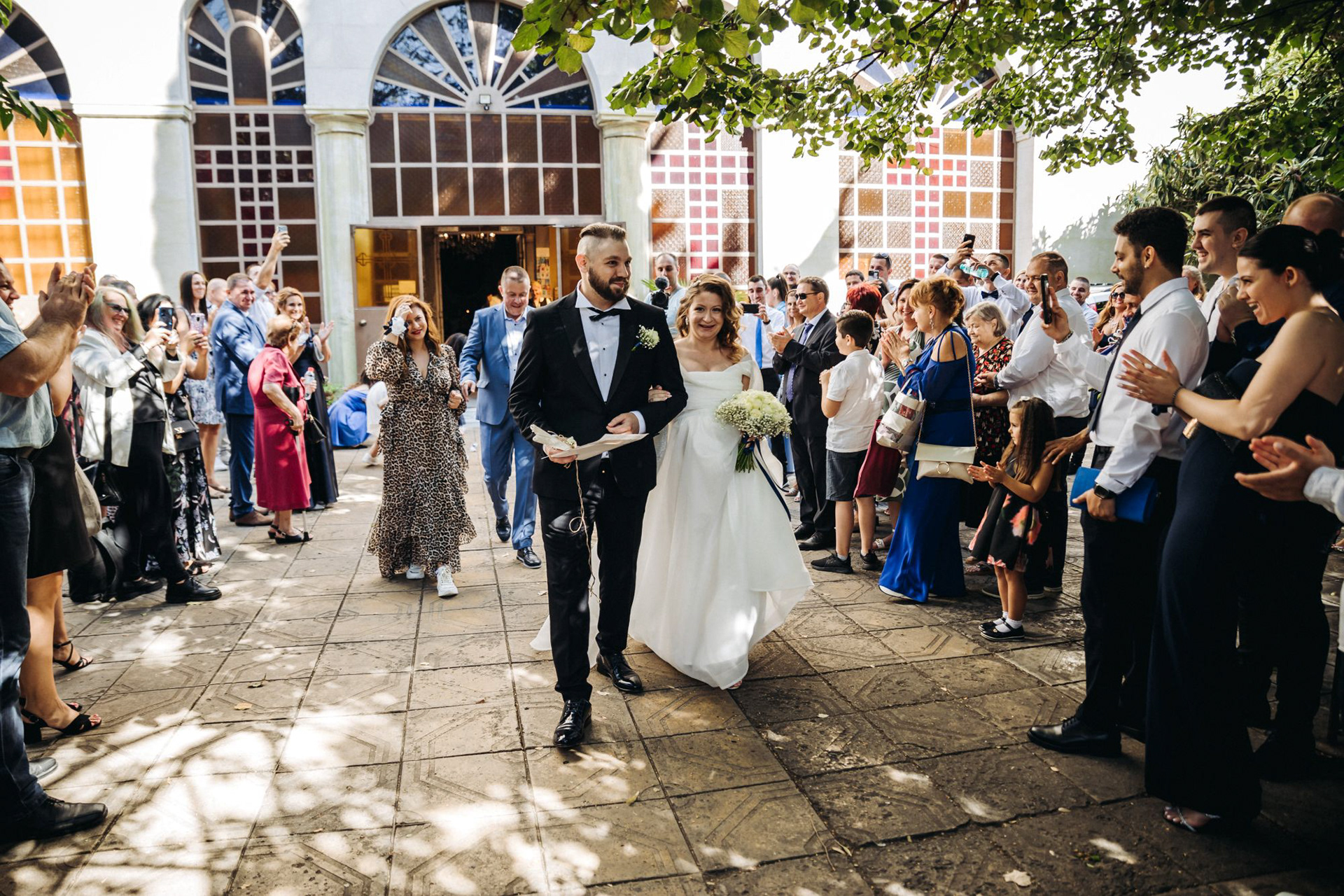 Излизане от църквата на младоженци в Бургас – сватбен фотограф Габриел Александров заснема емоционален момент с гости и аплодисменти.