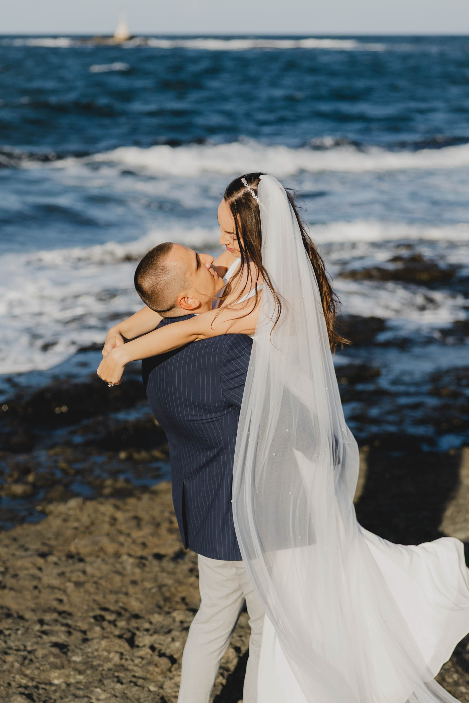 Сватбена снимка на скалите в Царево – младоженец вдига булката на фона на морския хоризонт, фотография Габриел Александров