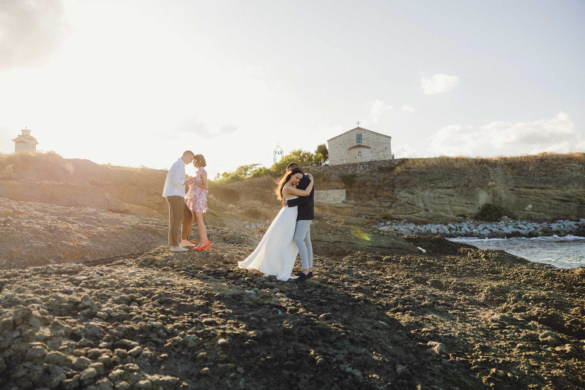 Кумове и младоженци в кратък танц на скалите в Царево, на фона на Храм "Свето Успение Богородично"