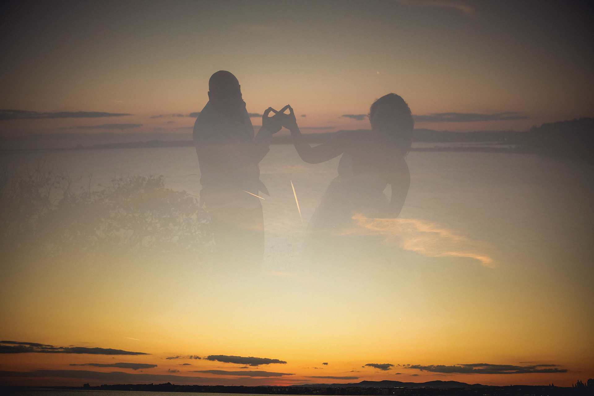 Артистична сватбена фотография с двойна експозиция по залез в Несебър – силуети на младоженци, образуващи символа за безкрайност с ръце на фона на прелитащи самолети. Креативен сватбен фотограф Несебър – Габриел Александров