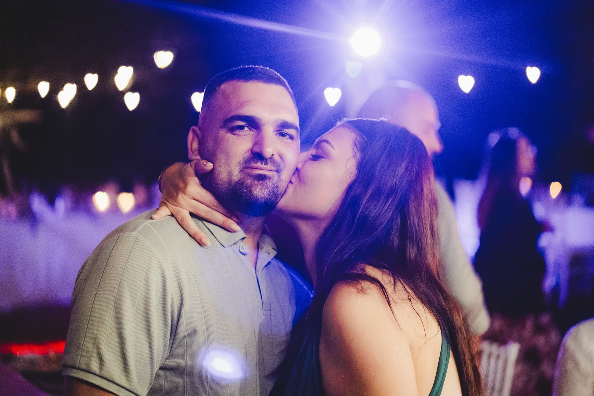 Кумата е влюбено целува кума - артистична сватбена фотография с фон на сърца