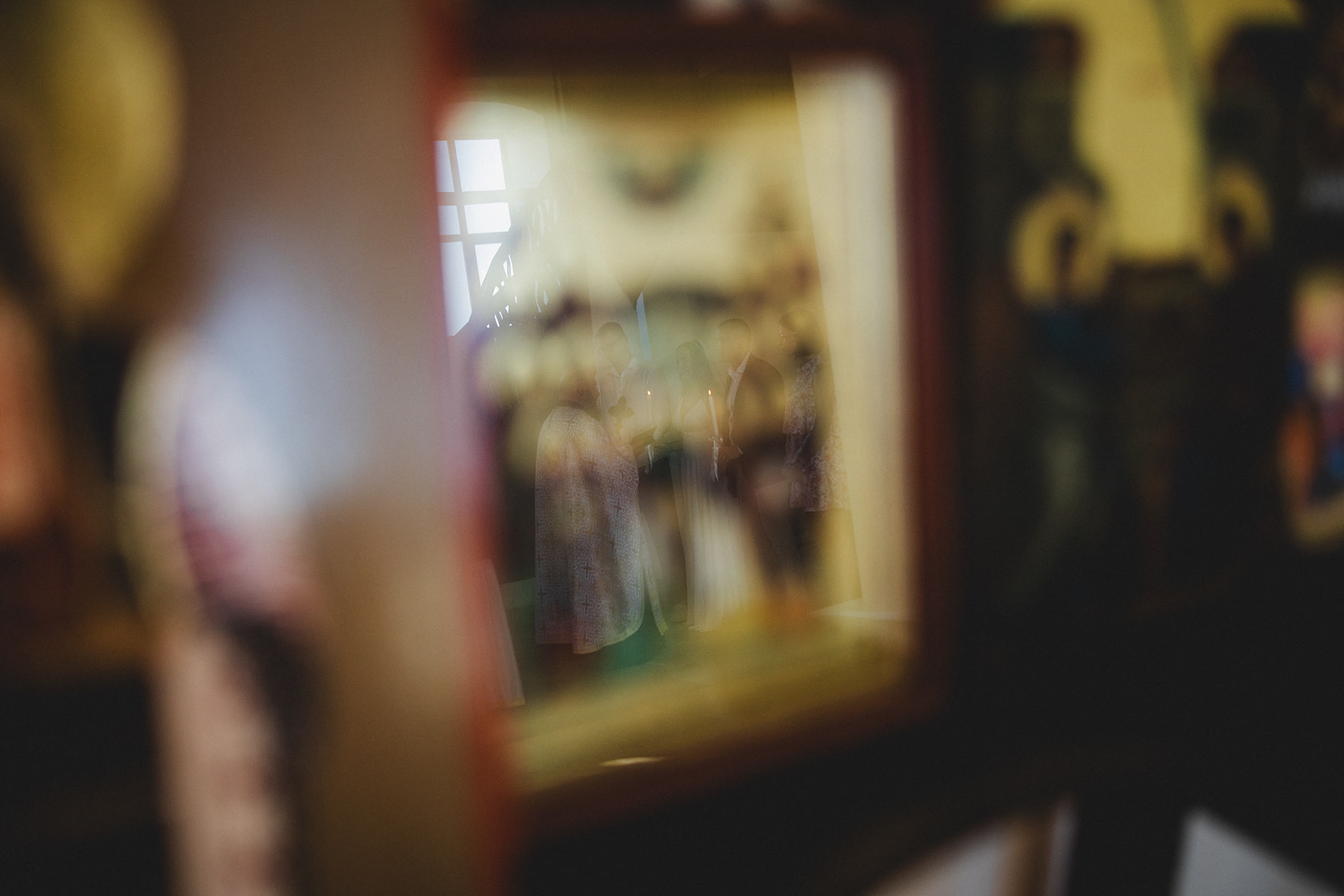 Артистичен кадър от венчавка в Царево – отражение на младоженците и свещеника в икона, църковен брак в храм Св. Успение Богородично