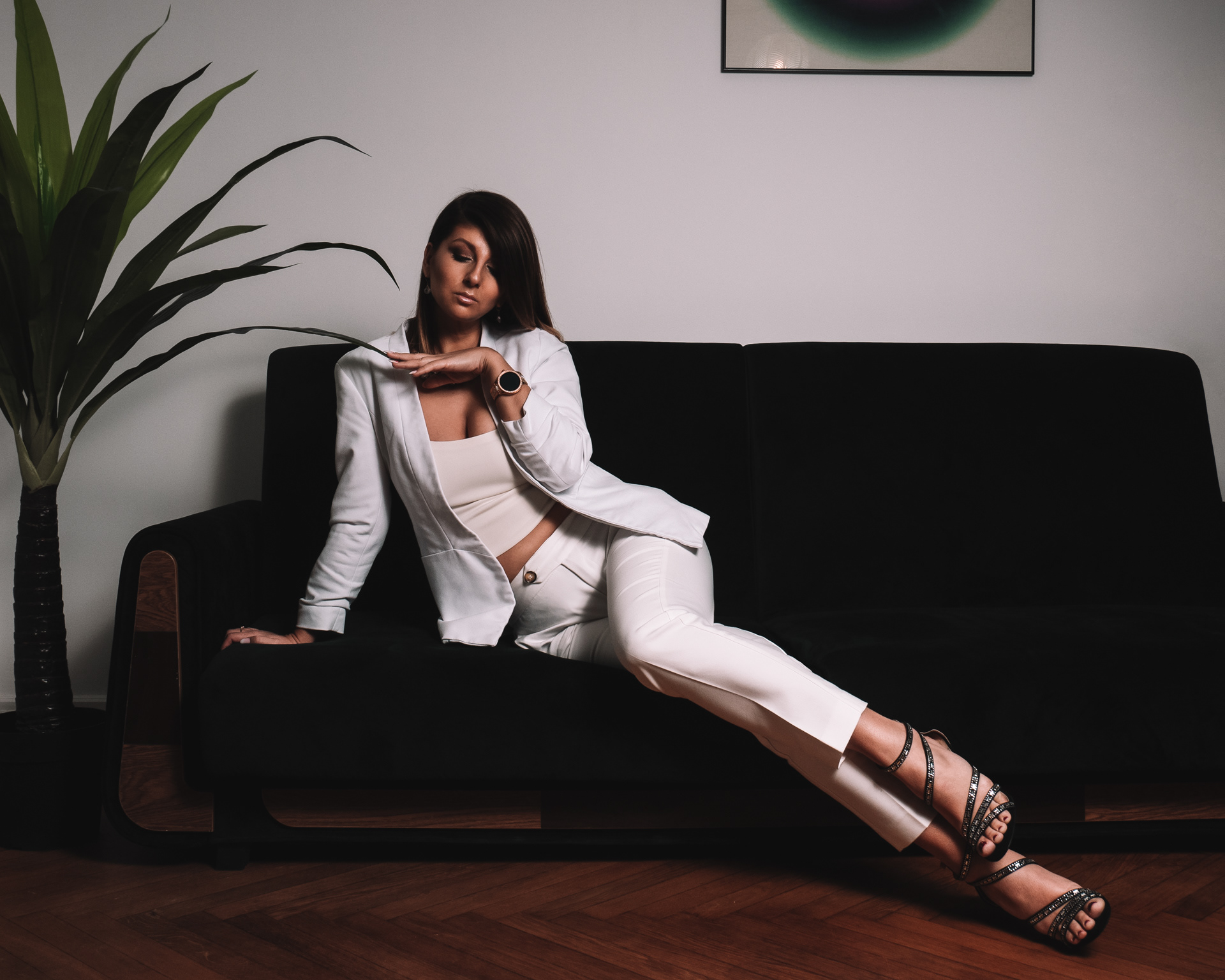 Sesja sensualna kobiety w białym garniturze siedzącej na łóżku w apartamencie w Warszawie. Fotograf Warszawa