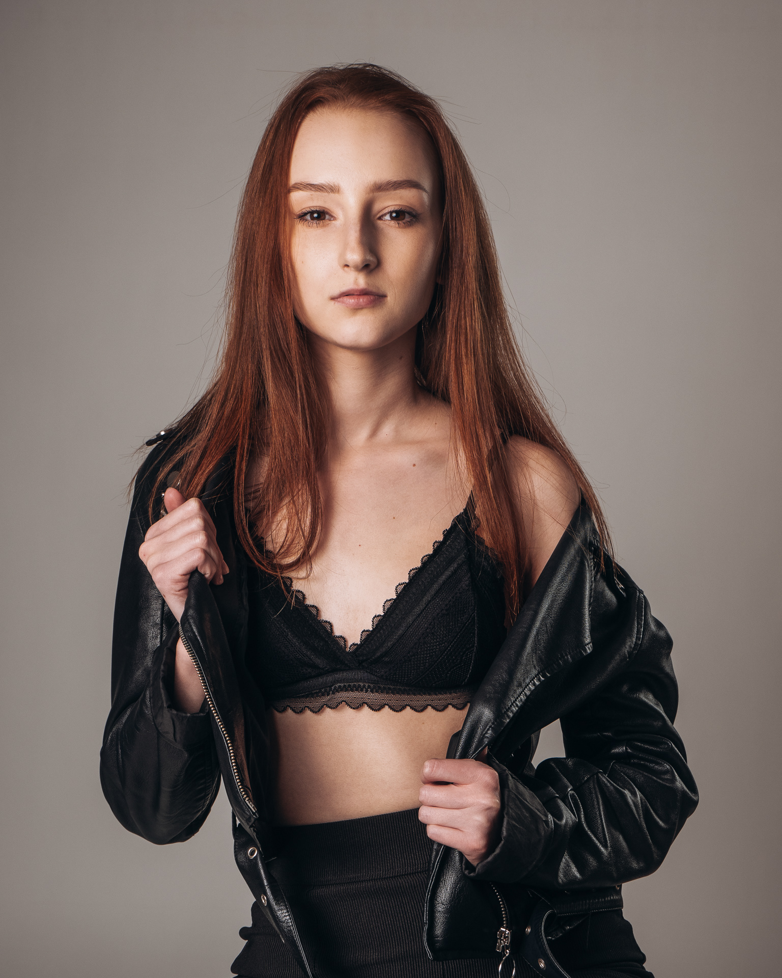 Sesja studyjna - portret kobiety w czarnej kurtce i czarnej bieliźnie na ciemnym tle. Fotograf Warszawa