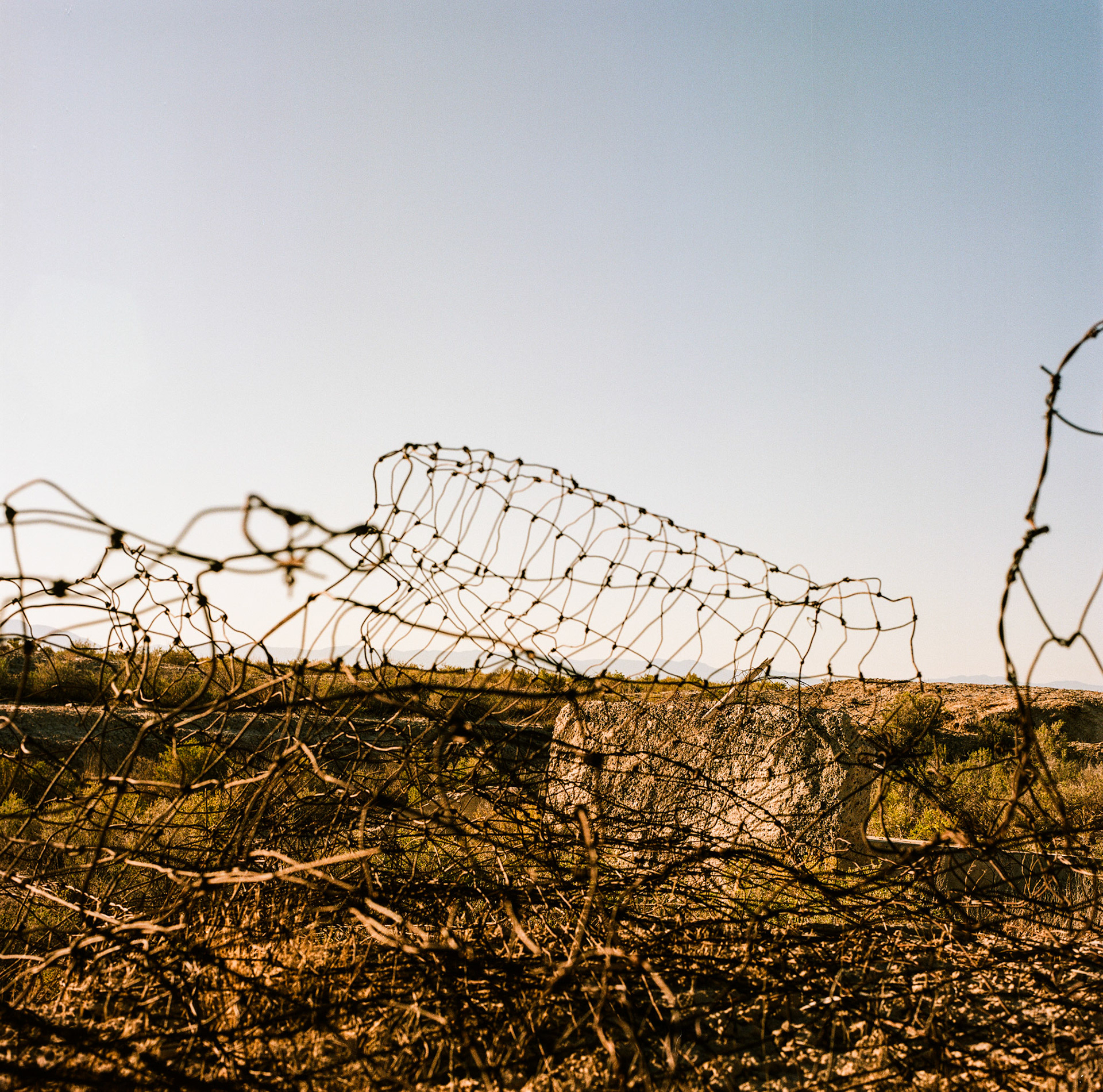 It's Analog Tuesday... Here's the foundation of one of the buildings of the Topaz Internment Camp looking through fencing that once surrounded the camp. Lets not forget what happens when a nation builds camps like these.