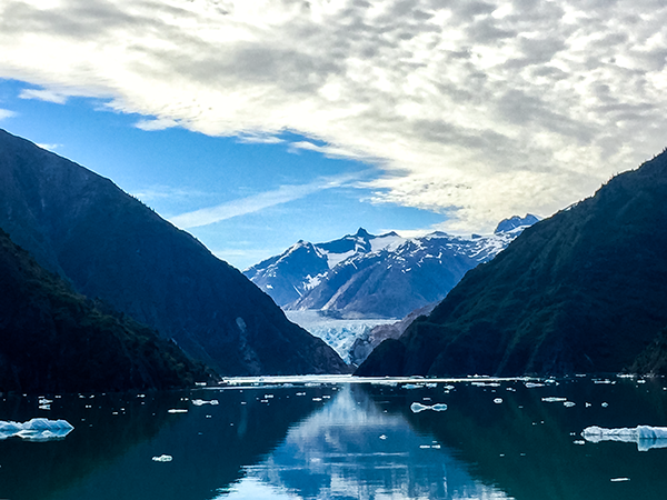Landscape photograph of an Alaskan glacier emphasizing striking color contrast, natural symmetry, and the dramatic scale of the surrounding mountains.