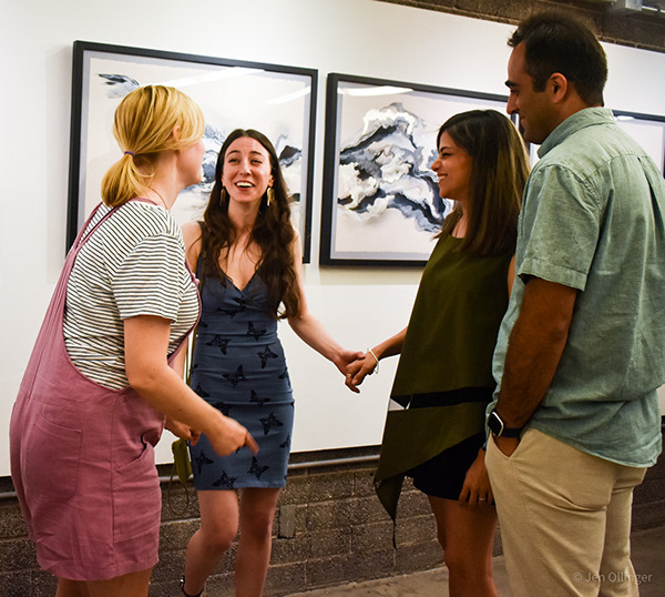 Candid portrait capturing the artist's genuine reaction while welcoming friends to the gallery opening.