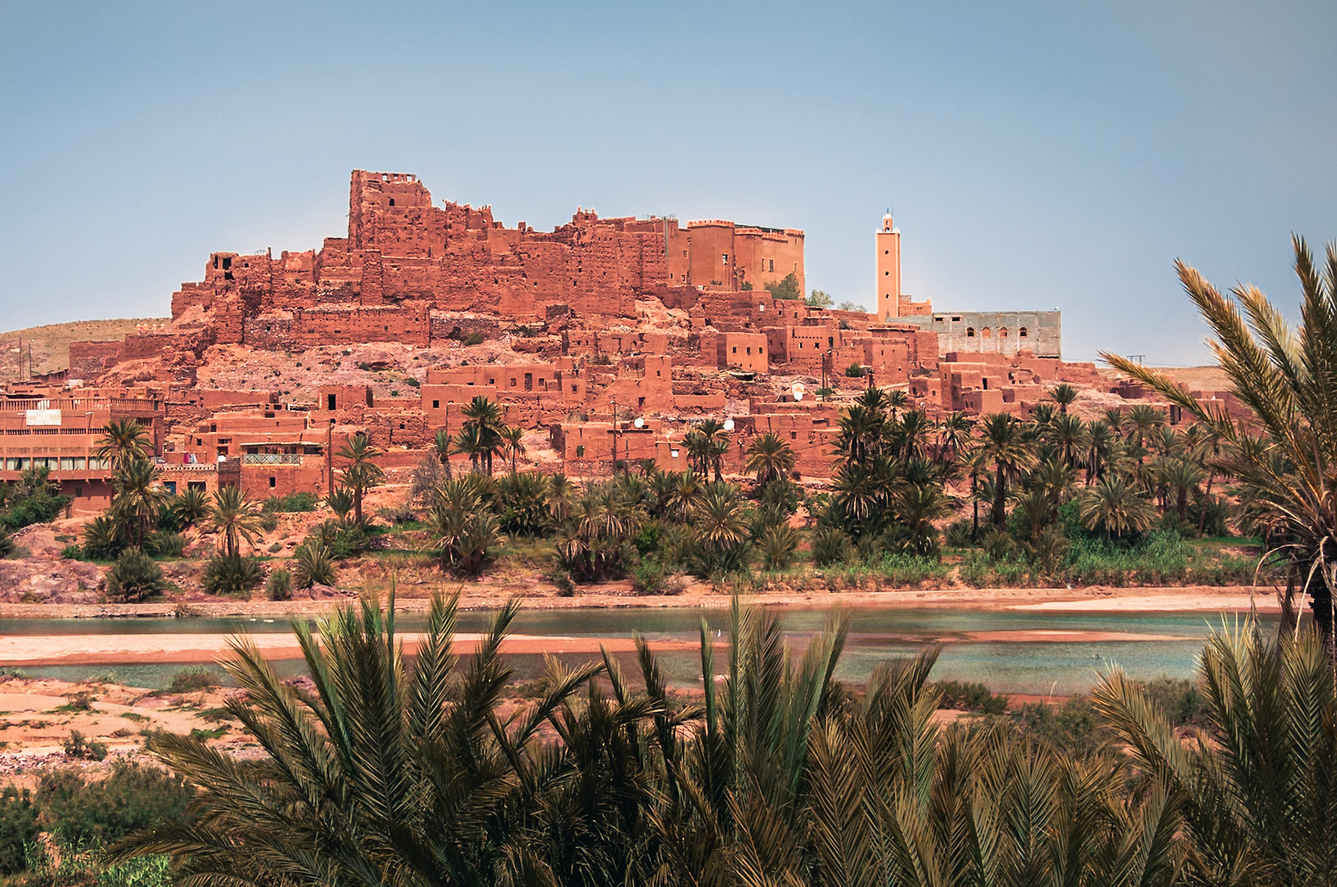 (EN) Aït Benhaddou is a fortified city, or palace (ksar), along the former caravan route between the Sahara and Marrakech in present-day Morocco. Most citizens living in the area now live in more modern dwellings in a nearby village, although there are 4 families still living in the ancient city. This giant fortification, which is made up of six forts (Kasbahs) and nearly fifty palaces which are individual forts, is a great example of earthen clay architecture, which is also used in Moroccan architecture.Aït Benhaddou has been a UNESCO World Heritage Site since 1987 and several films have been shot there, including:Gladiator, The Mummy, Babel, Prince of Persia, etc.(ES) Ait Ben Hadu es una "ciudad fortificada" o Ksar. Se encuentra en la provincia de Ouarzazate, entre las provincias de Tata y Marrakech, en la región de Souss-Massa-Draâ en Marruecos. Se extiende a lo largo del río Ounila. La mayoría de los habitantes de la ciudad viven en el nuevo pueblo al otro lado del río, sin embargo, algunas familias aún viven dentro del Ksar.Ait Ben Hadu es Patrimonio de la Humanidad declarado por la Unesco en el año 1987 y se han rodado varias películas famosas en el lugar como: Gladiador, La Momia, Babel, Principe de Persia, etc.