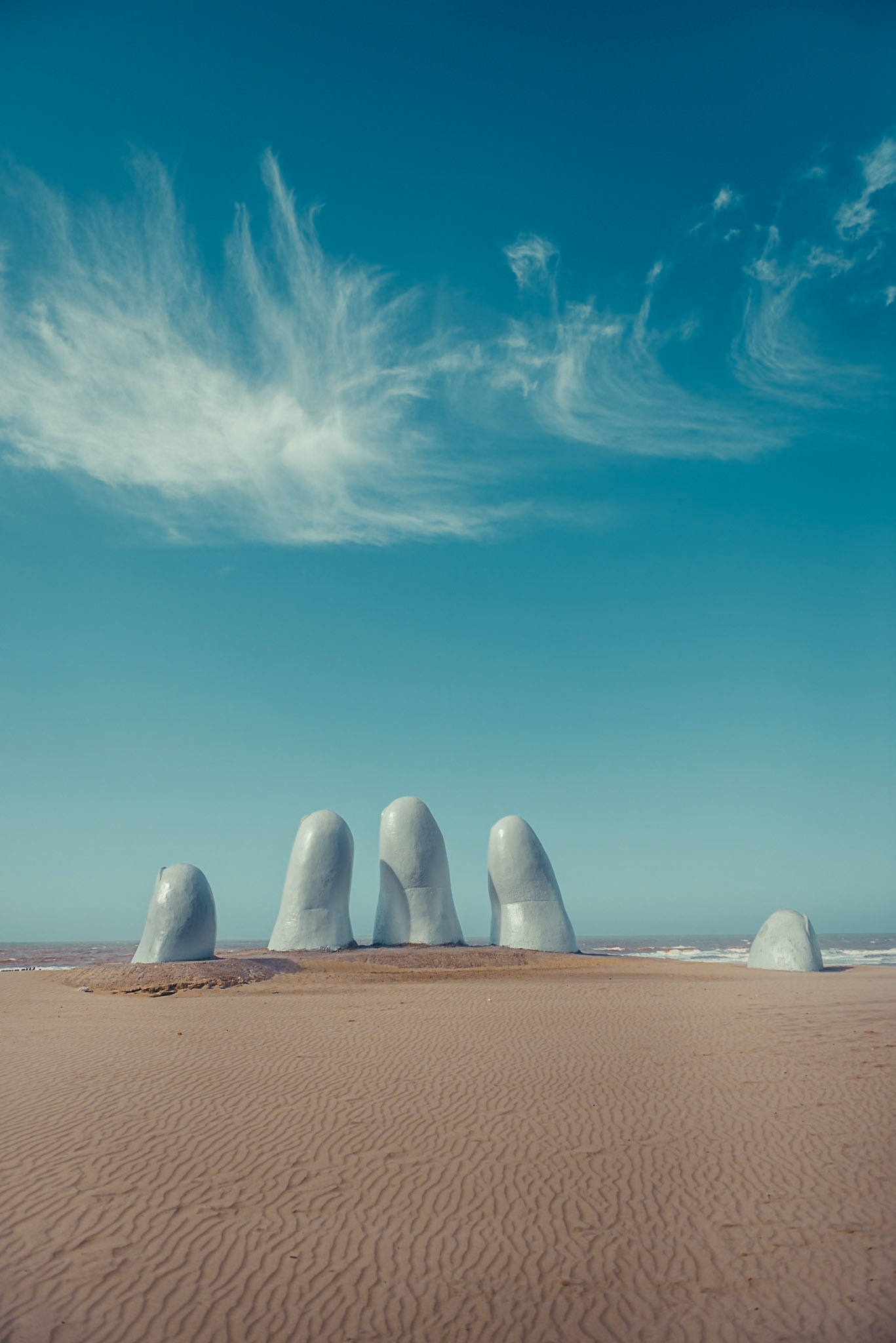 (EN) "Mano de Punta del Este" (Hand of Punta del Este) is a sculpture of five human fingers partially emerging from sand, is located on Parada 1 at Brava Beach in Punta del Este, a popular resort town in Uruguay. It is also known as either "Monumento de los Dedos" (Monument of the Fingers), "Monumento al Ahogado" (Monument to the Drowned) or, "Hombre Emergiendo a la Vida" (Man Emerging into Life). This famous sculpture was made by Chilean artist Mario Irarrázabal and has become a symbol for Punta del Este since its completion in February 1982 and in turn has become one of Uruguay's most recognizable landmarks.(ES) "La Nano" es una escultura de cinco dedos parcialmente sumergidos en arena, localizada en la parada 1 de la playa Brava en Punta del Este, un popular balneario turístico en Uruguay. También es conocída como "Los Dedos", "Monumento al ahogado" u "Hombre Emergiendo a la Vida" Esta famosa escultura fue hecha por el artista chileno Mario Irarrázabal y se convirtió en símbolo para Punta del Este desde su acabado en febrero de 1982, además de transformarse en uno de los puntos de referencia más reconocibles de ese país.