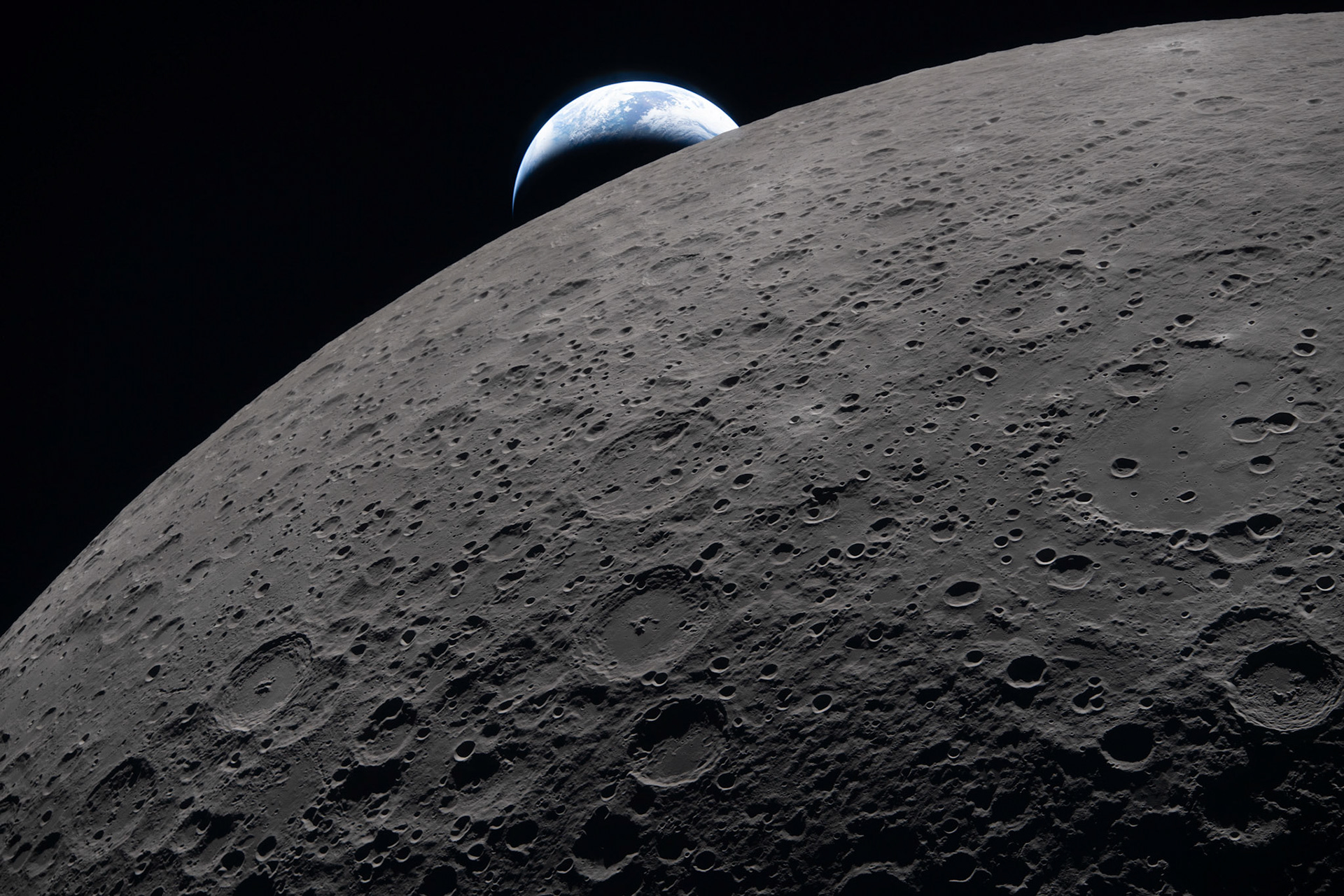 art002e009289 (April 6, 2026) – The lunar surface fills the frame in sharp detail, as seen during the Artemis II lunar flyby, while a distant Earth sets in the background. This image was captured at 6:41 p.m. EDT, on April 6, 2026, just three minutes before the Orion spacecraft and its crew went behind the Moon and lost contact with Earth for 40 minutes before emerging on the other side.In this image, the dark portion of Earth is experiencing nighttime, while on its day side, swirling clouds are visible over the Australia and Oceania region. In the foreground, Ohm crater shows terraced edges and a relatively flat floor marked by central peaks — formed when the surface rebounded upward during the impact that created the crater.