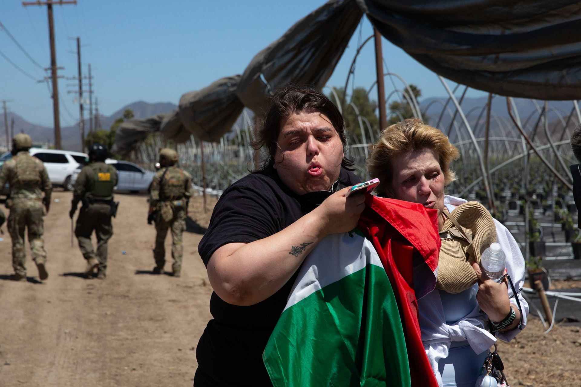 Mother escorts her daughter who is suffering an asthma attack after ICE and DHS agents fire tear gas at civilians gathered on a farm. DHS agents from multiple subsidiaries conducts a mass raid at a farm in Camarillo, Calif. on July 10, 2025.