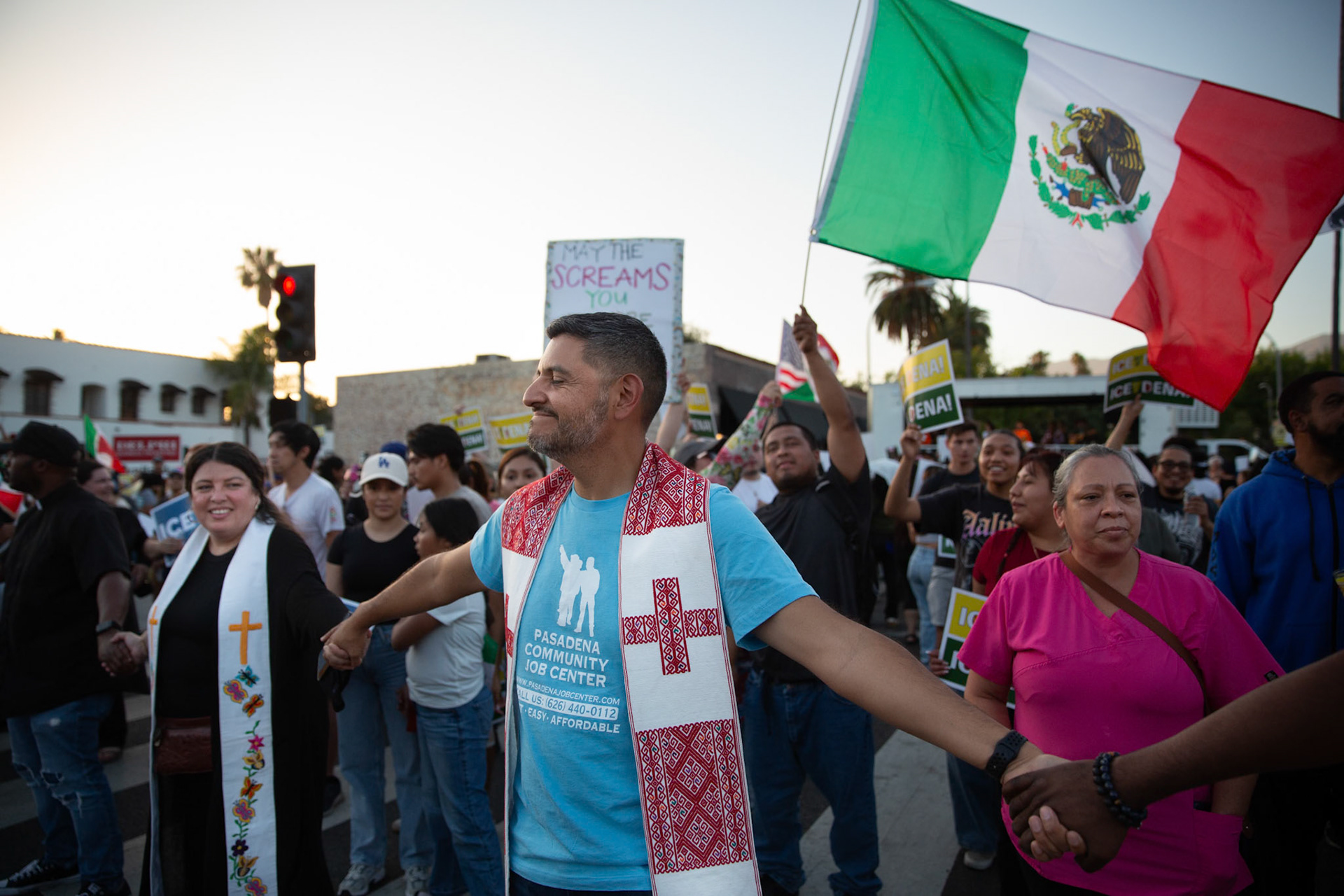 Pastor Marcos Canales of La Fuente Ministreies and Mayra Macedo-Nolan of Clergy Community Coalition hold hands with clergy from various local religious demoniations to form a human chain in Pasadena, Calif. on June 18, 2025 to demonstrate against immigration raids conducted by ICE and Federal police. Canales says he is attending the demonstration because god had to flee as an migrant and the immigrants of the United States deserve recognition for their contribition to the country.