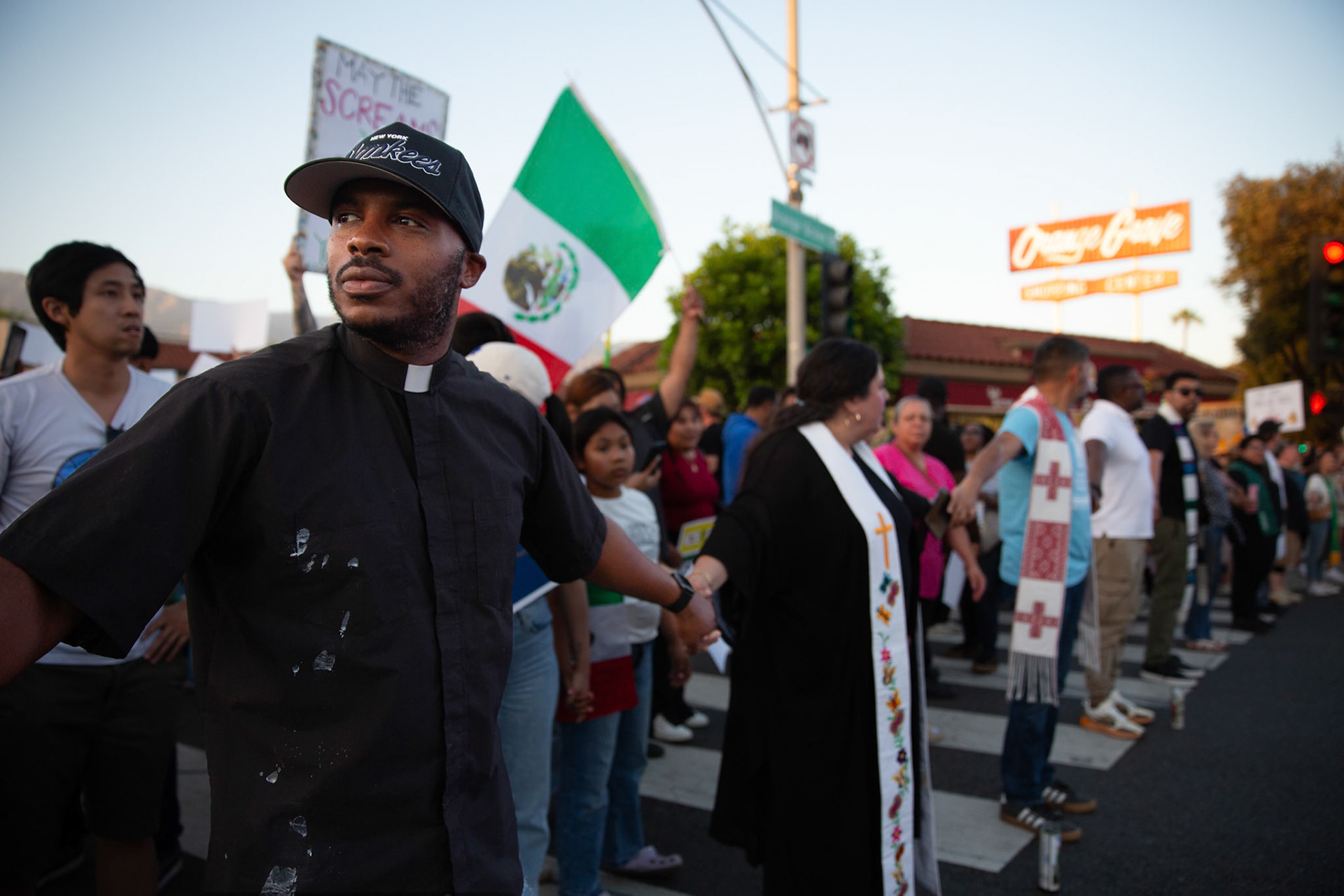 Rev. Mark Chase of All saints Church hold hands with clergy from various local religious demoniations to form a human chain in Pasadena, Calif. on June 18, 2025 to demonstrate against immigration raids conducted by ICE and Federal police. Chase says he is attending the demonstration because he was compelled by his faith and love for his community to stand against the abuse of rights. "This is where Jesus would be." says Chase.
