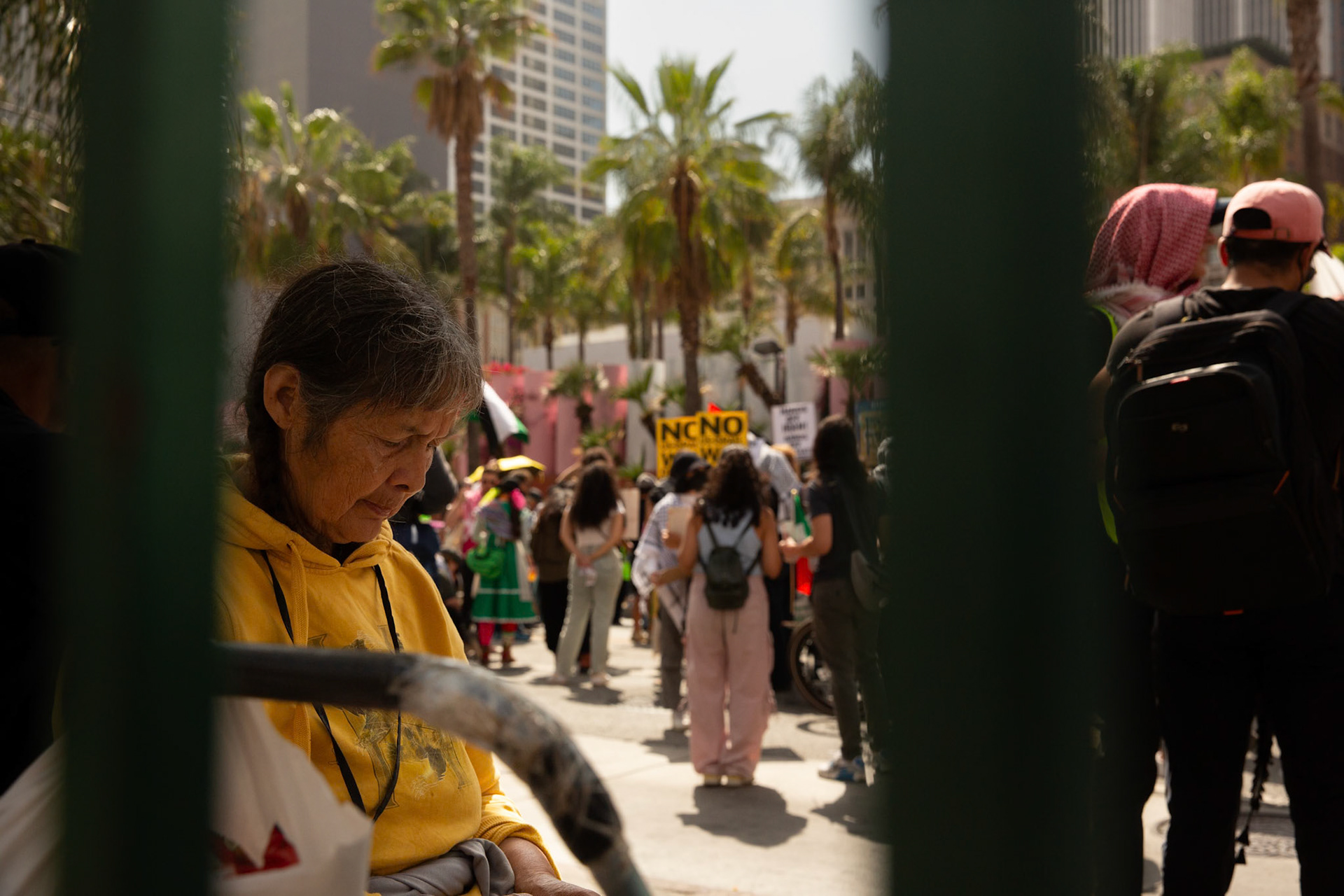 A commuter waits for the bus as demonstrators gather at Pershing Square in Los Angeles Calif. on June 21, 2025 during a demonstration against U.S. involvement in the war between Israel and Iran.