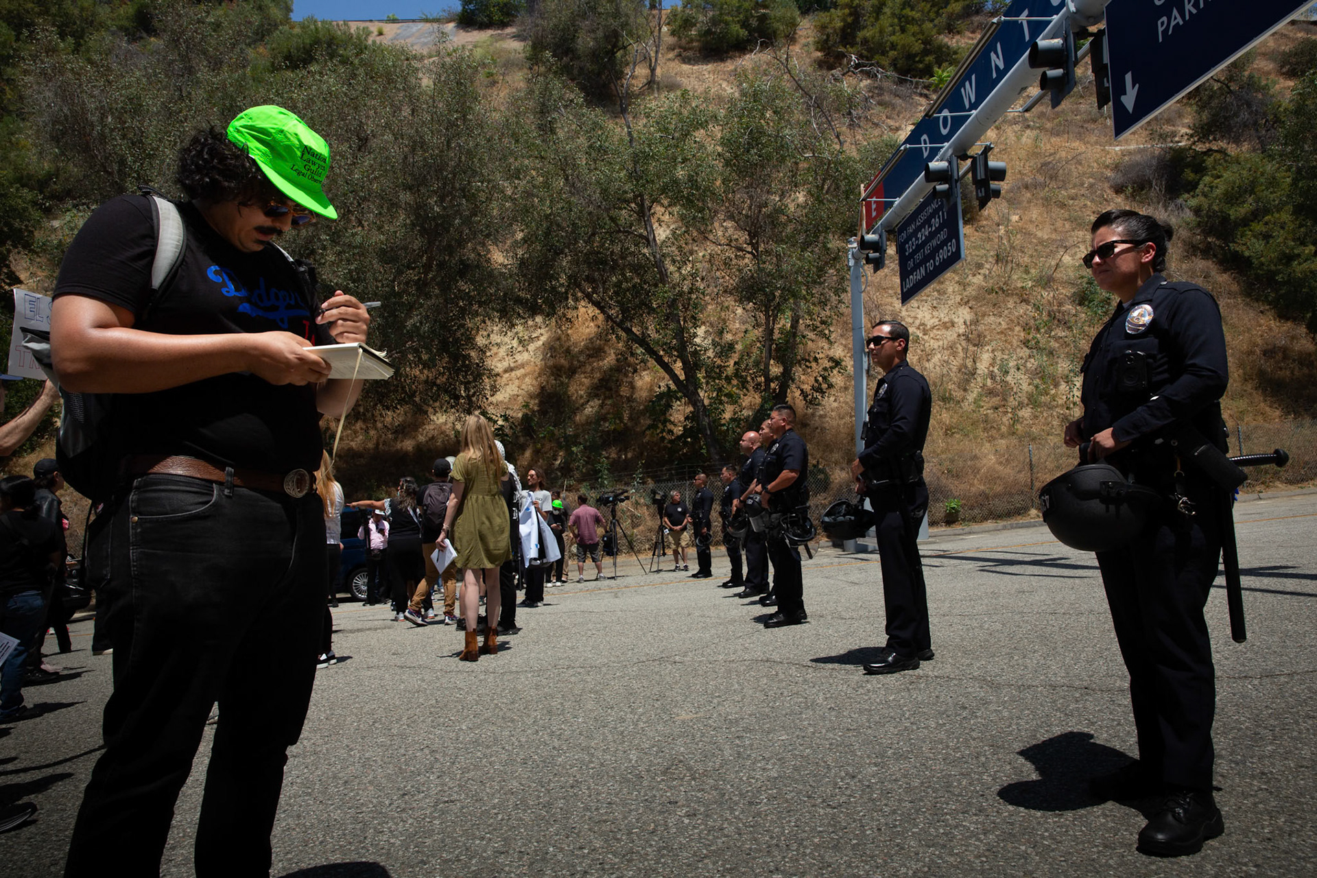 A legal observer from the National Lawyers Guild Los Angeles writes down name and badge numbers of LAPD officers. Border Patrol agents are trapped at Gate E of the Dodgers Stadium in Los Angeles, Calif. while attempting to set up a staging area oon June 19, 2025. A statement from Dodgers Team News website during the stand off states that the Dodgers has denied ICE agents access to the stadium. The Border Patrol agents pictured refuse to identify themselves but says they do not have anyone detained. Dodgers Stadium employees at the gate says they have not helped immigration agents and the stadium policy does not allow immigration agents on the property.