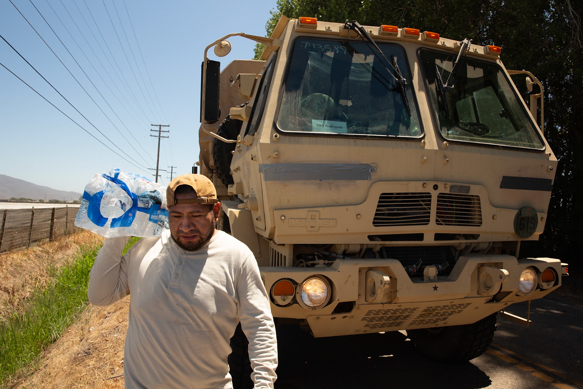 Man carries water for protestors and family members looking for their loved ones. DHS agents from multiple subsidiaries conducts a mass raid at a farm in Camarillo, Calif. on July 10, 2025.