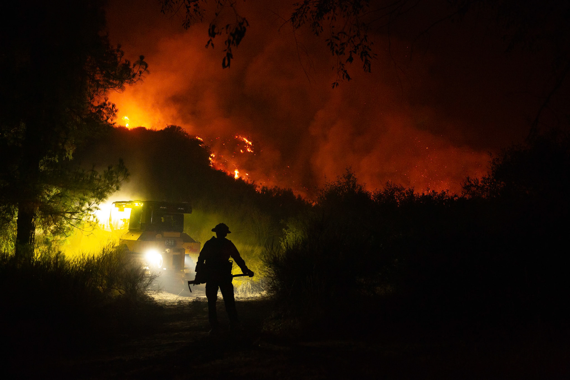 Firefighters use bulldozers and hand tools to remove vegetation in order prevent the wildfire from reaching nearby homes. The Canyon Fire started around 1:30pm on August 7, 2025 and rapidly spread to 600 acres in less than two hours. Aided by the heatwave in Southern California that reached 100 degrees Ferehnehit, dry vegetation, and steep topology; the fire has scorched more than 4,800 acres as of Thursday night.