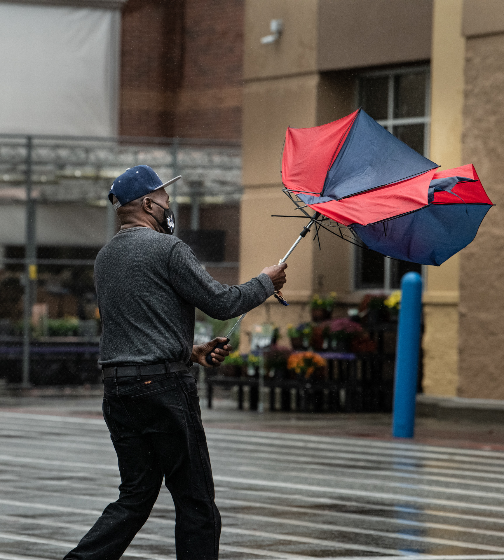 A man's umbrella is caught by the wind as he walks into Walmart in High Point, N.C. on October 29, 2020. A tropical storm warning was put into place for High Point, N.C. through Thursday October 29, 2020 at 7:15 PM.