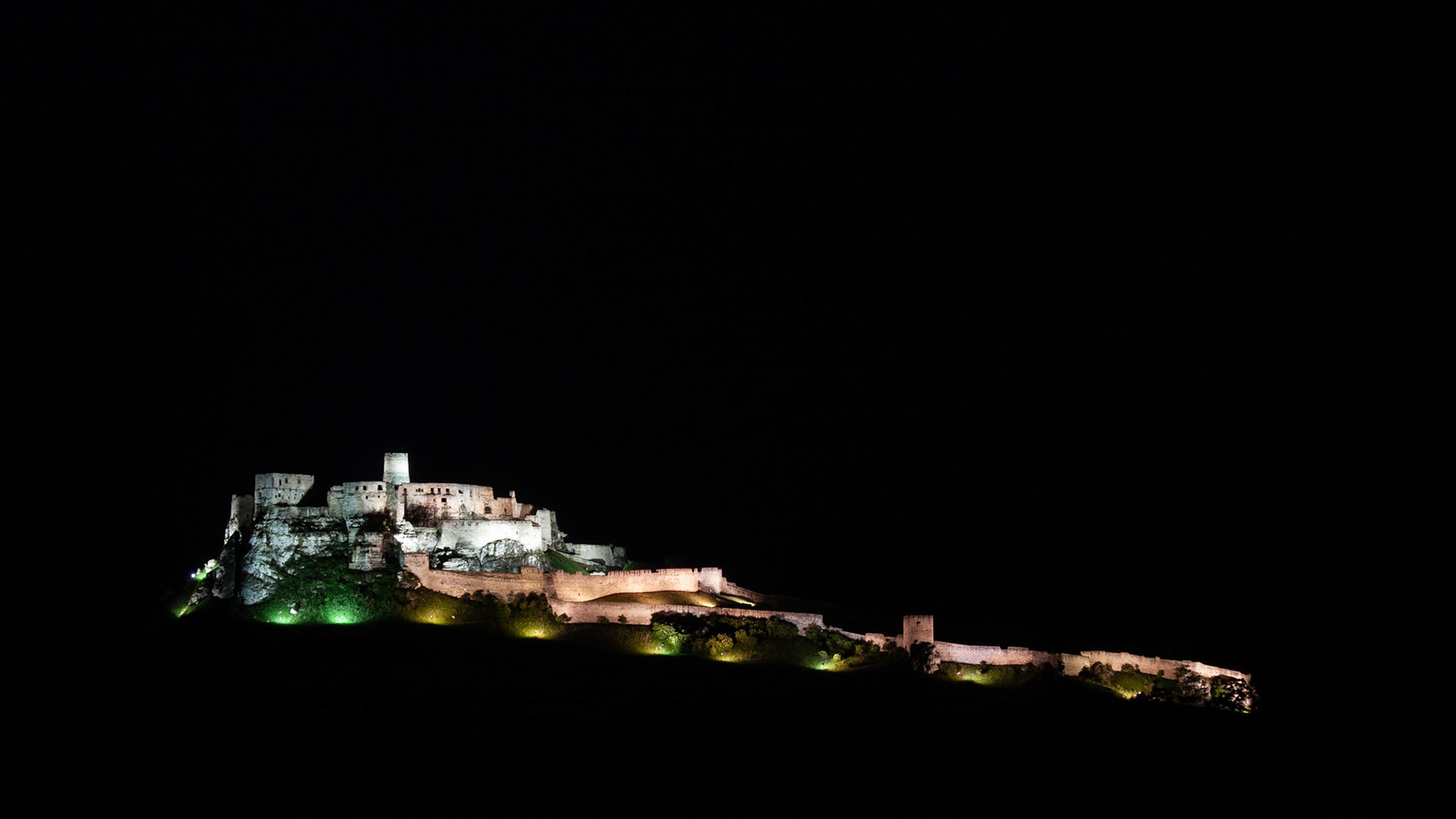 A lit up Spis Castle seems to float in the surrounding darkness
