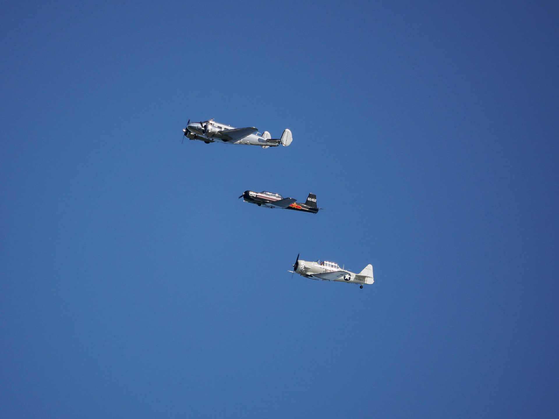 Vintage airplanes flying overhead near what used to be an old airfield (but which is now a wildlife refuge).
