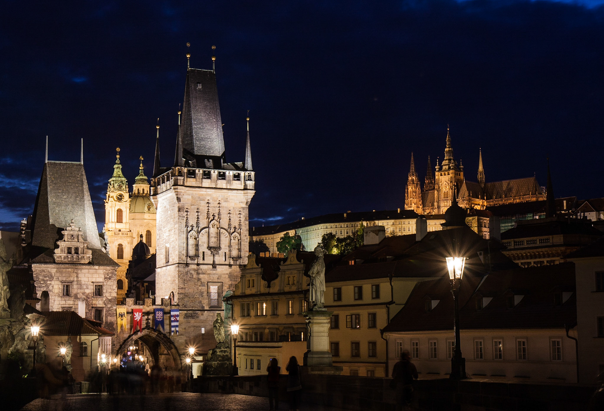 The Lesser Town Bridge Tower and St. Vitus shine brightly in the night