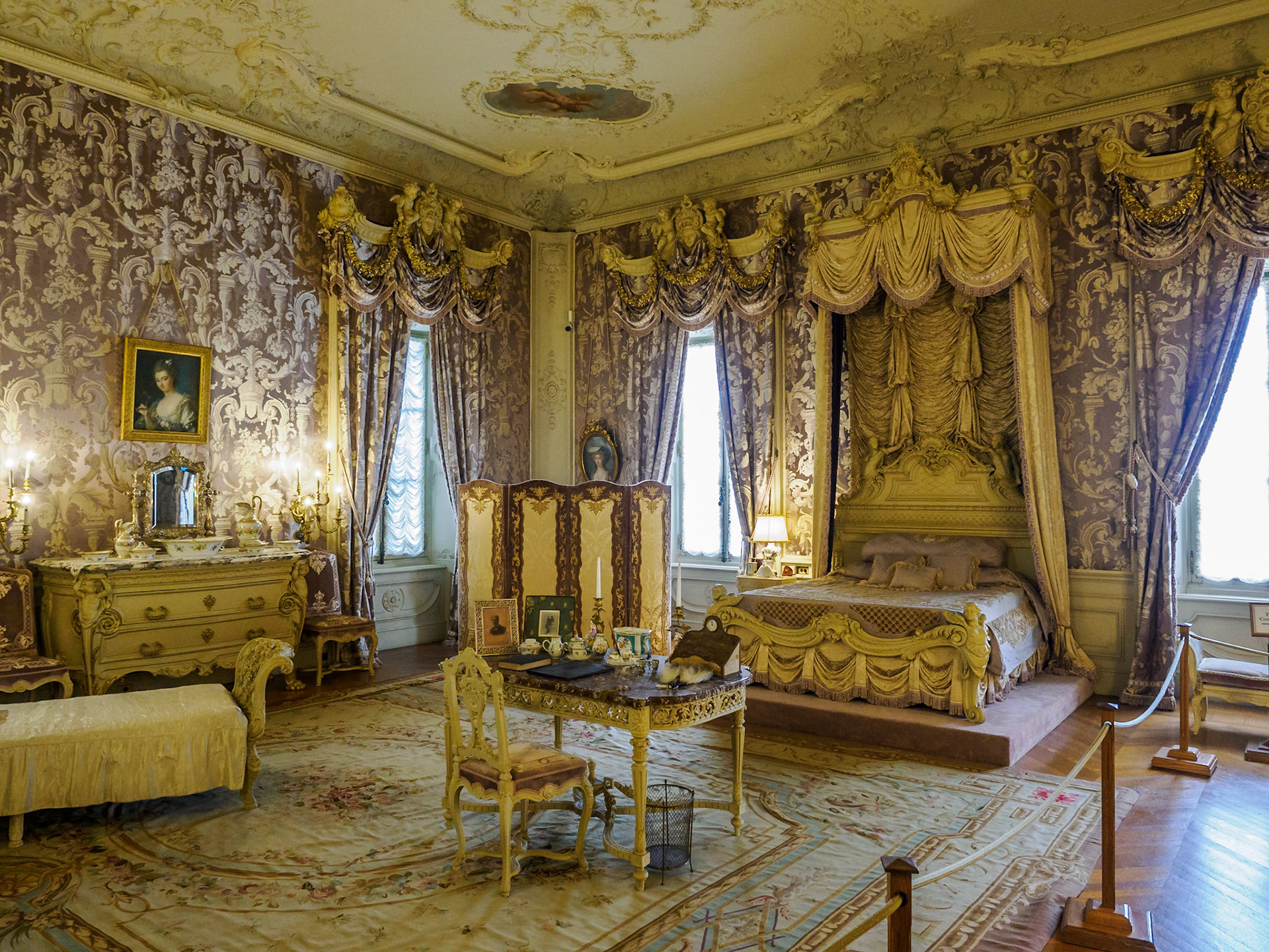 Alva Vanderbilt created a lilac bedroom for herself. It is decorated with garlands, nymphs, and cherubs. Her bed sits on a platform, like a throne.