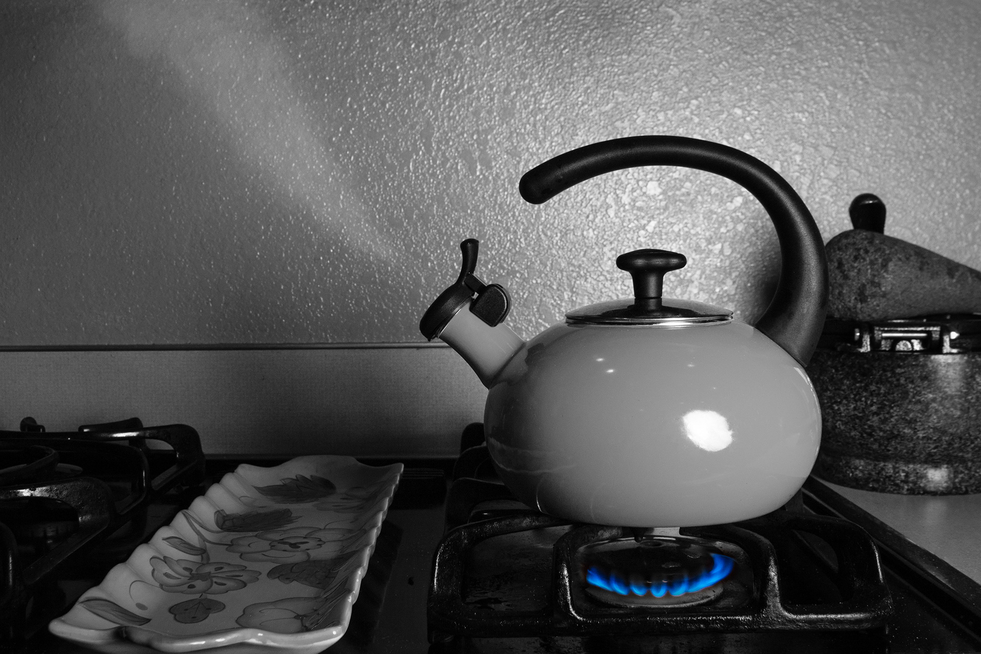 In Their Absence - In wait upon the stove sits the tea kettle whistling for the person who lit its flame. Though the flame heated the kettle, evoking the whistle, a hand ignited the flame, but the hand that caused the flame to spark is no longer in sight.