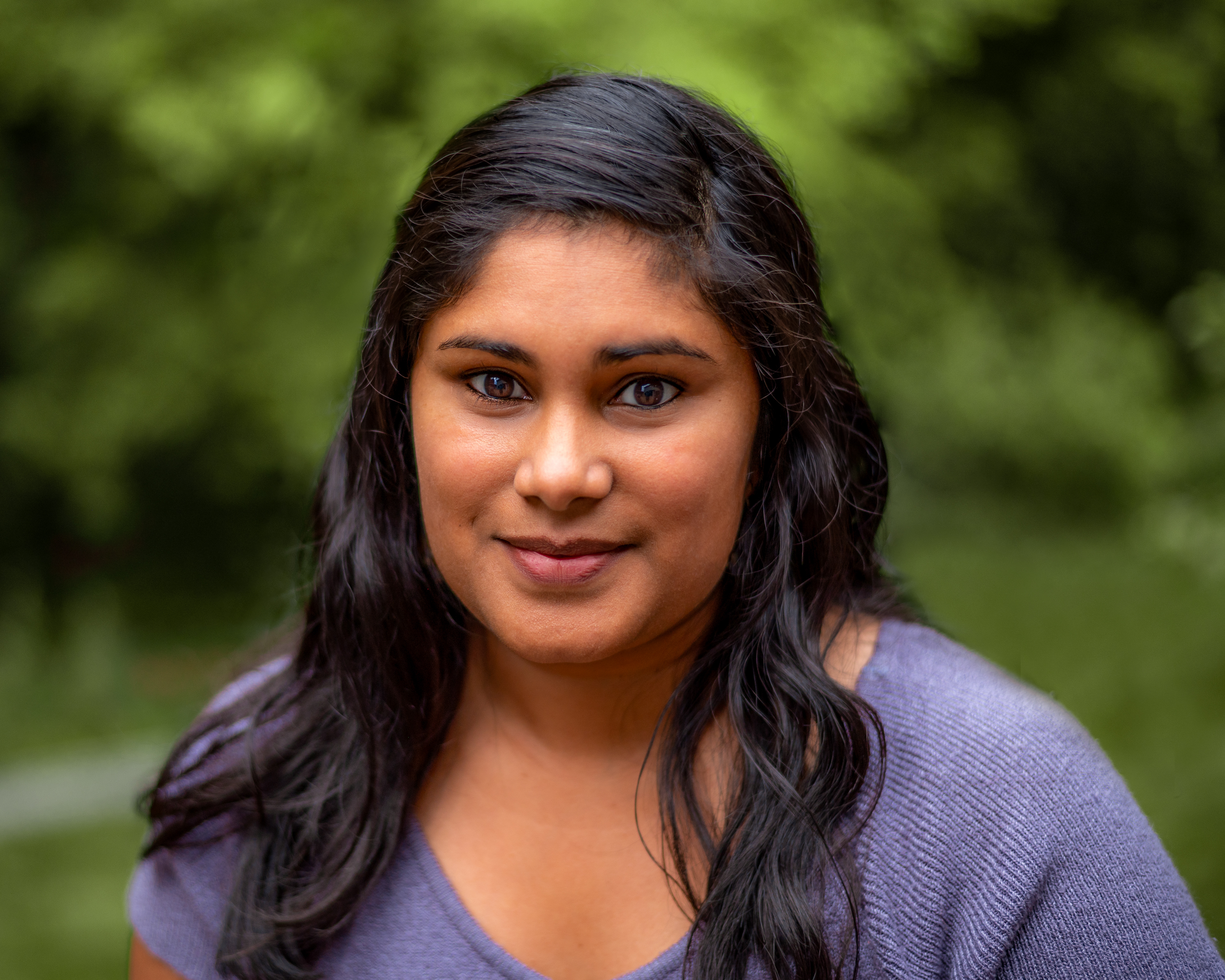 Jyoti Bock with black wavy hair and a light purple sweater